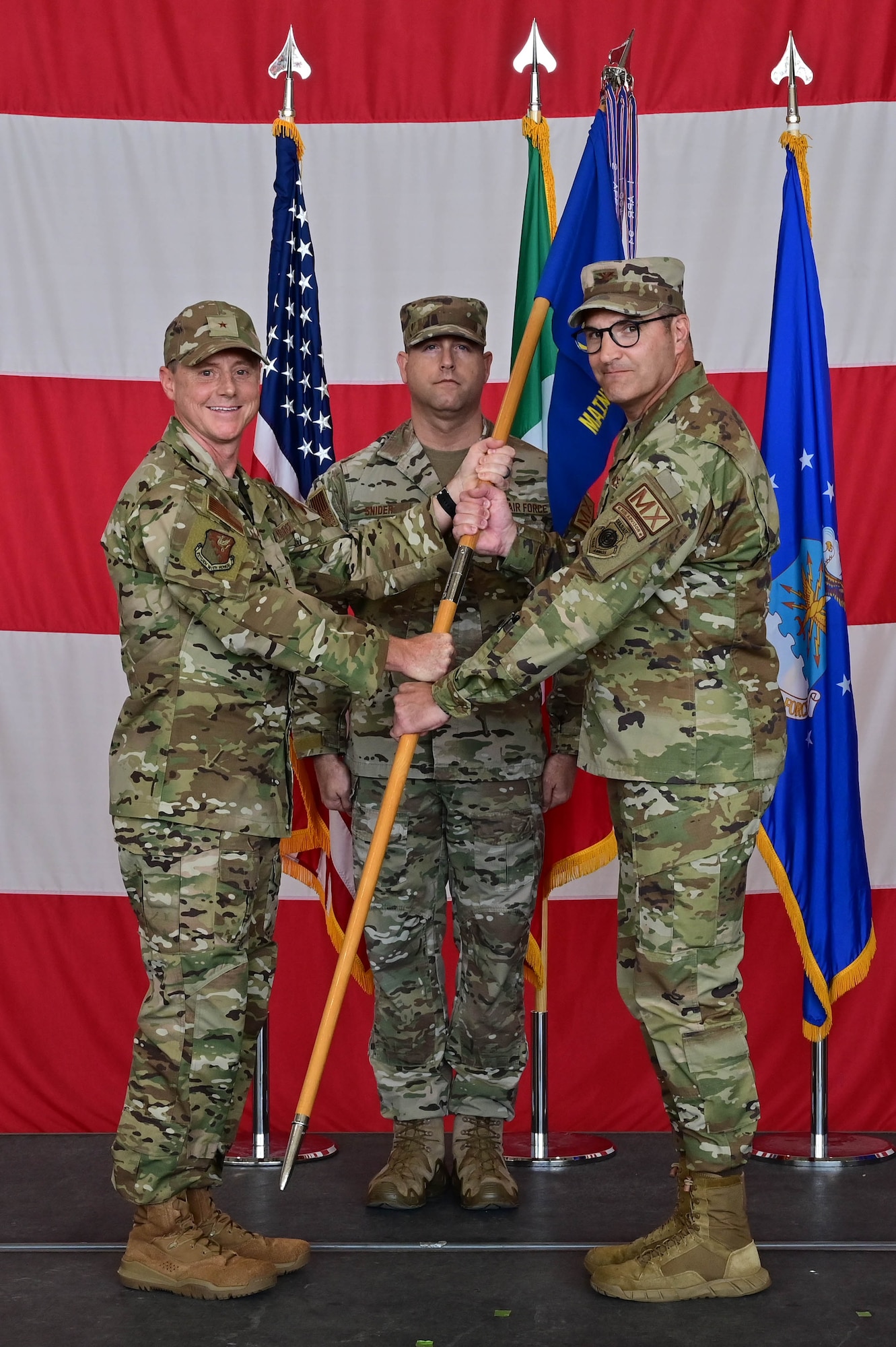U.S. Air Force Brig. Gen. Tad Clark, 31st Fighter Wing commander, passes the guidon to U.S. Air Force Col. Joe Stangl, 31st Maintenance Group incoming commander, to symbolize the changing of command at Aviano Air Base, Italy, June 15, 2023. The 31st Maintenance Group maintains combat capability for 56 combat-coded F-16 and HH-60 aircraft and provides force infrastructure support for 1,600 military and civilian personnel assigned to 4 squadrons, including one geographically separated. (U.S. Air Force photo by Airman Zachary Jakel)