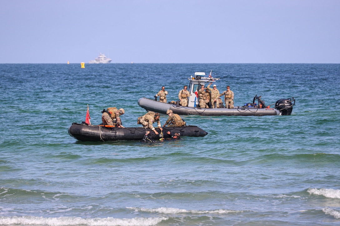 Service members travel through a body of water in two small inflatable boats.