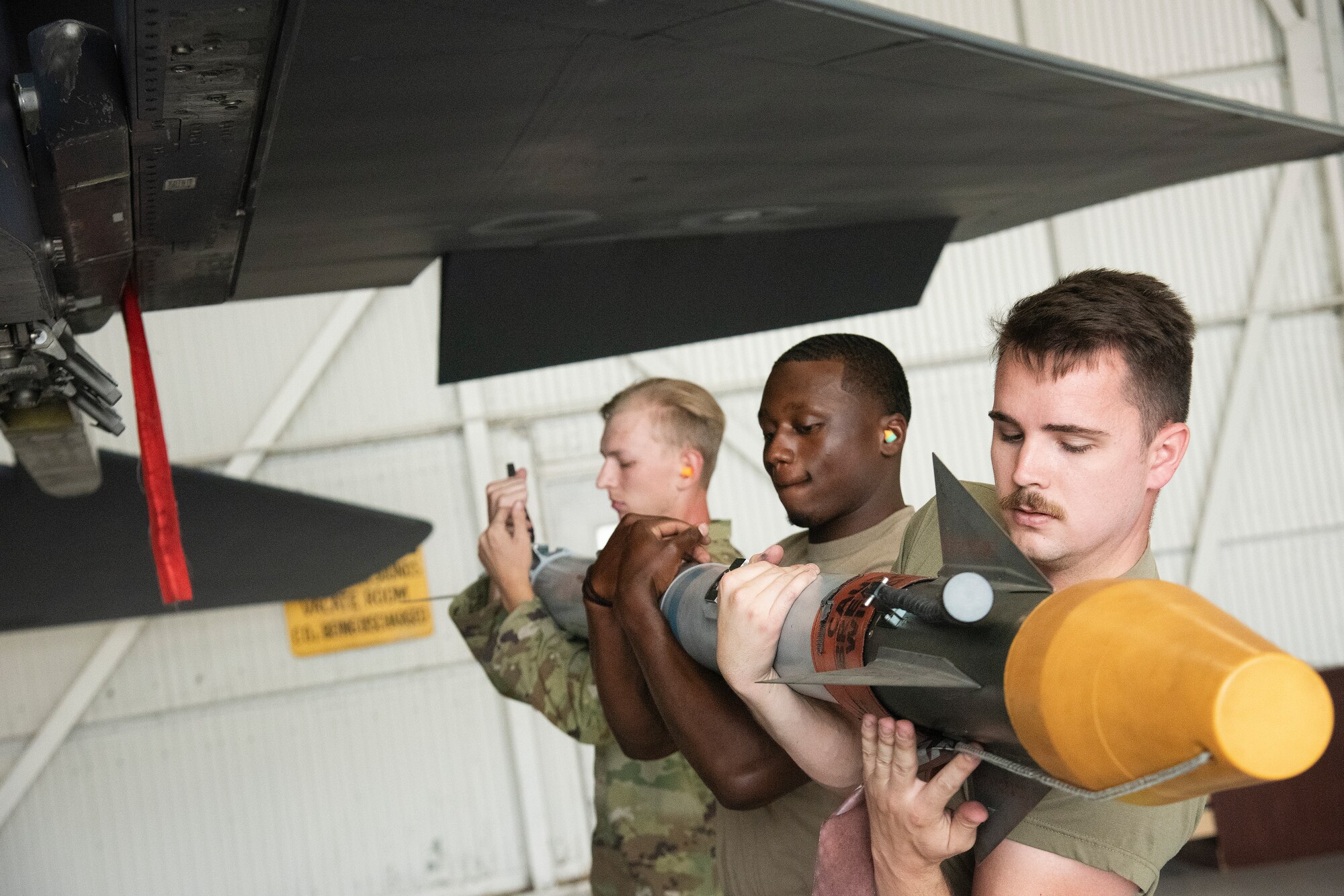 Senior Airman Mitchell Sanborn, right, Staff Sgt. Jashuann Jasper, center, and Airman 1st Class Isaac Bergfield, left, 335th Fighter Generation Squadron weapons load crew members, load unarmed practice [AIM-9X Sidewinder missile] munitions onto an F-15E Strike Eagle.