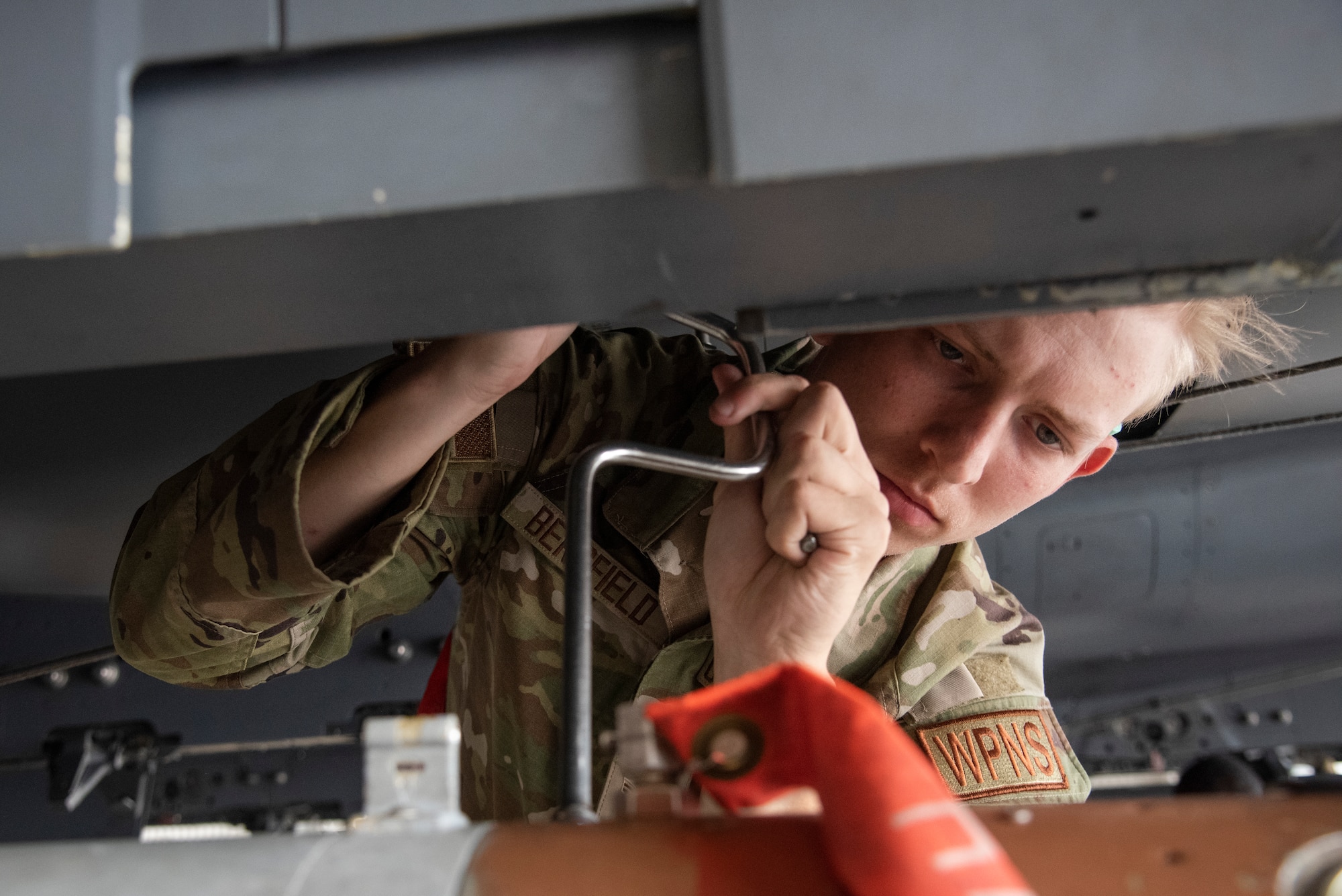 Airman 1st Class Isaac Bergfield, 335th Fighter Generation Squadron weapons load crew member, secures an unarmed practice [GBU-10 Paveway II] munition onto an F-15E Strike Eagle.