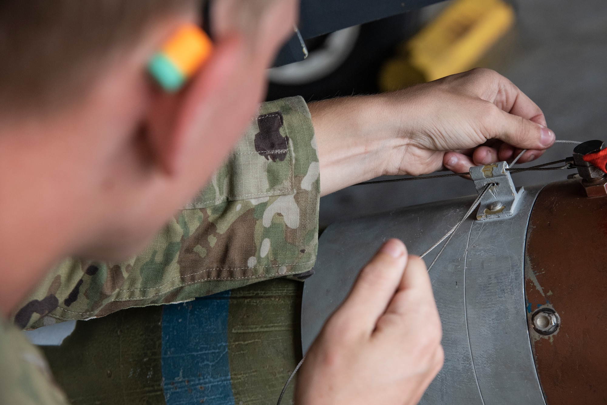 Airman 1st Class Isaac Bergfield, 335th Fighter Generation Squadron weapons load crew member, secures an unarmed practice [GBU-10 Paveway II] munition onto a F-15E Strike Eagle.