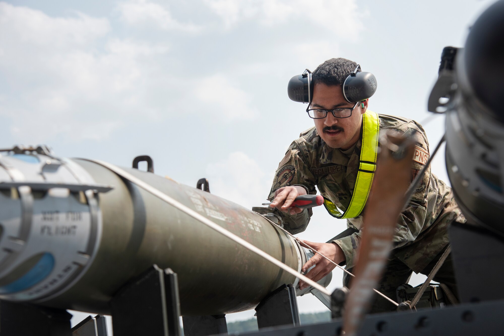 Airman 1st Class Jean Vega-Lopez, 336th Fighter Generation squadron weapons load crew member, inspects unarmed practice [GBU-38 JDAM] munitions.