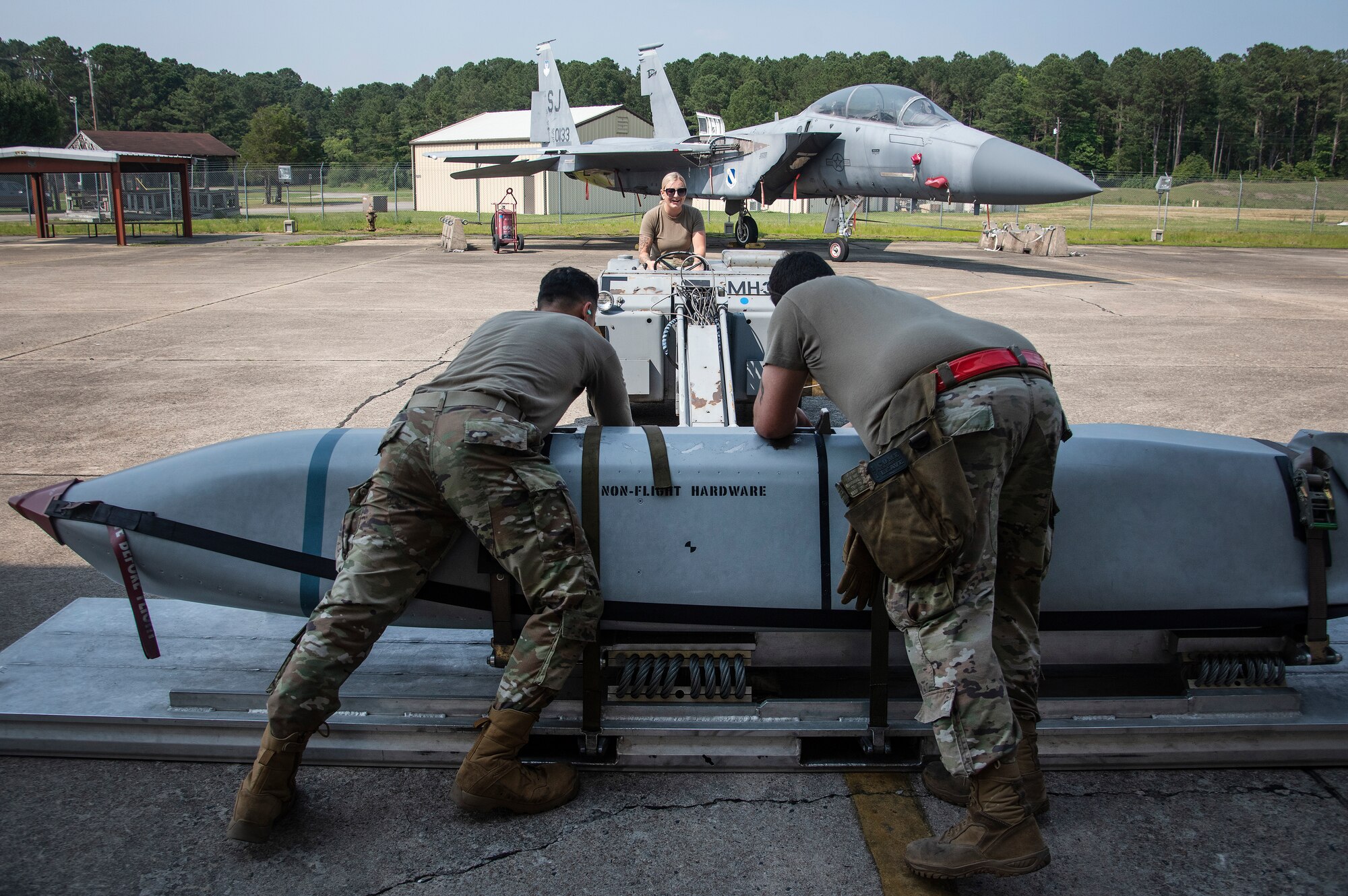 Senior Airman Kaylee Hanson, center, and Staff Sgt. Alexandro Diaz, left, 4th Maintenance Group loading standardization crew members, work alongside Staff Sgt. Miguel Jiminez Flores, 336th Fighter Generation squadron weapons load crew chief, to strap down an unarmed practice [AGM-158 JASSM] munition.