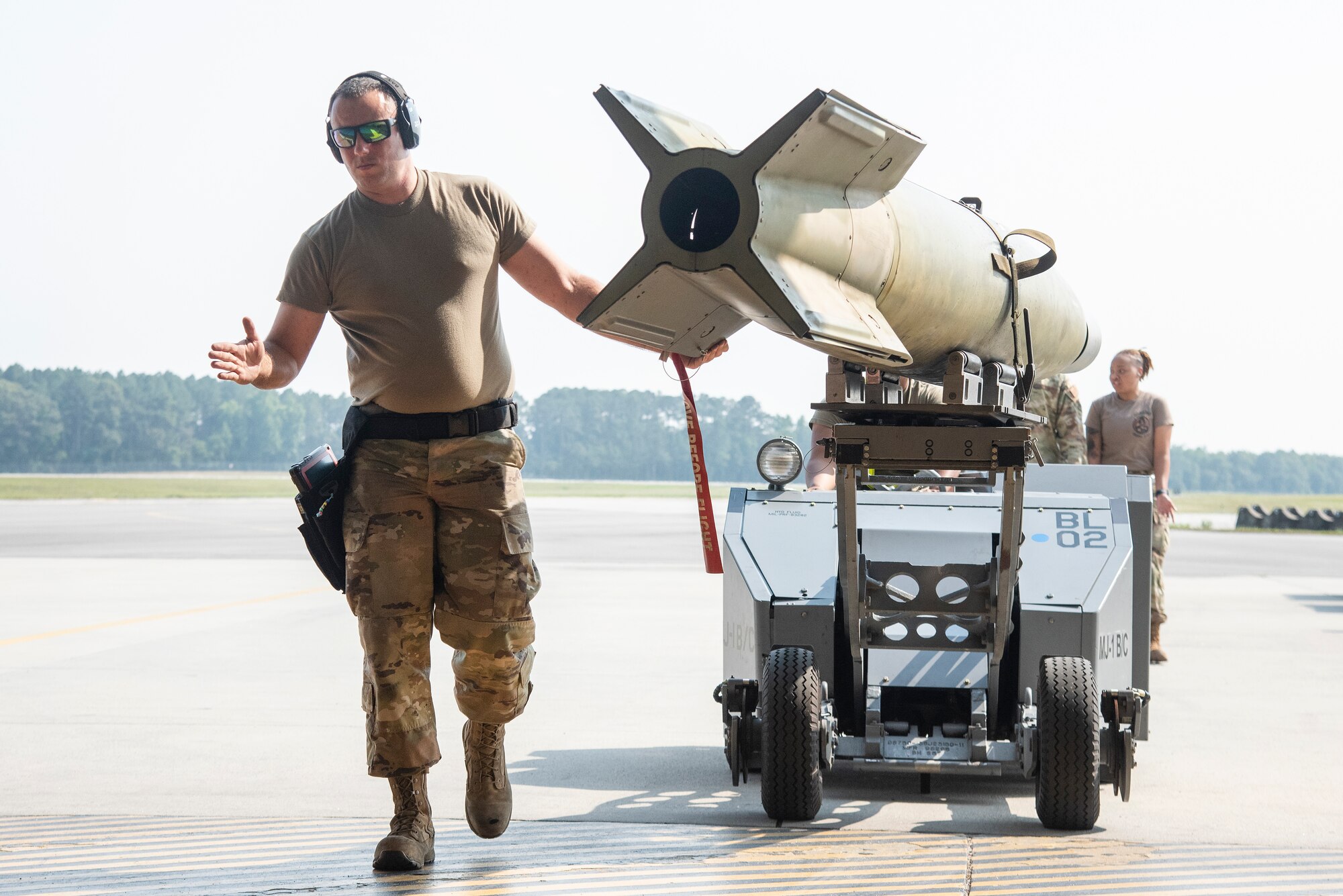 Staff Sgt. Jared Branch, 336th Fighter Generation Squadron weapons load crew chief leads an unarmed practice [GBU-10 Paveway II] munition into a hangar bay.