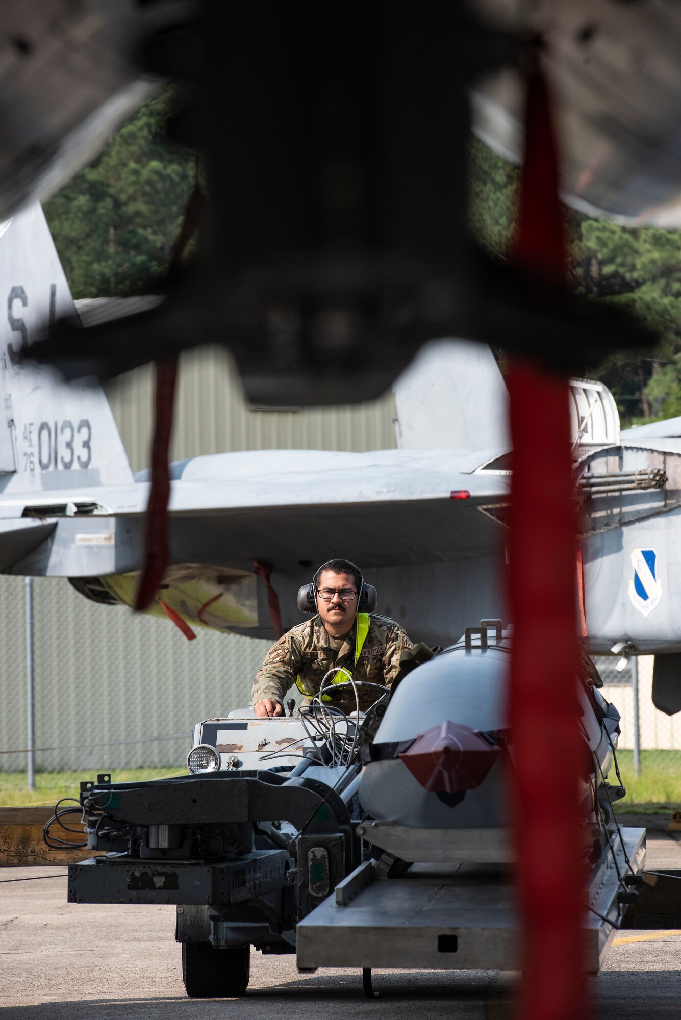 Airman 1st Class Jean Vega-Lopez, 336th Fighter Generation squadron weapons load crew member, transports an unarmed practice [AGM-158 JASSM] munition toward an F-15E Strike Eagle.