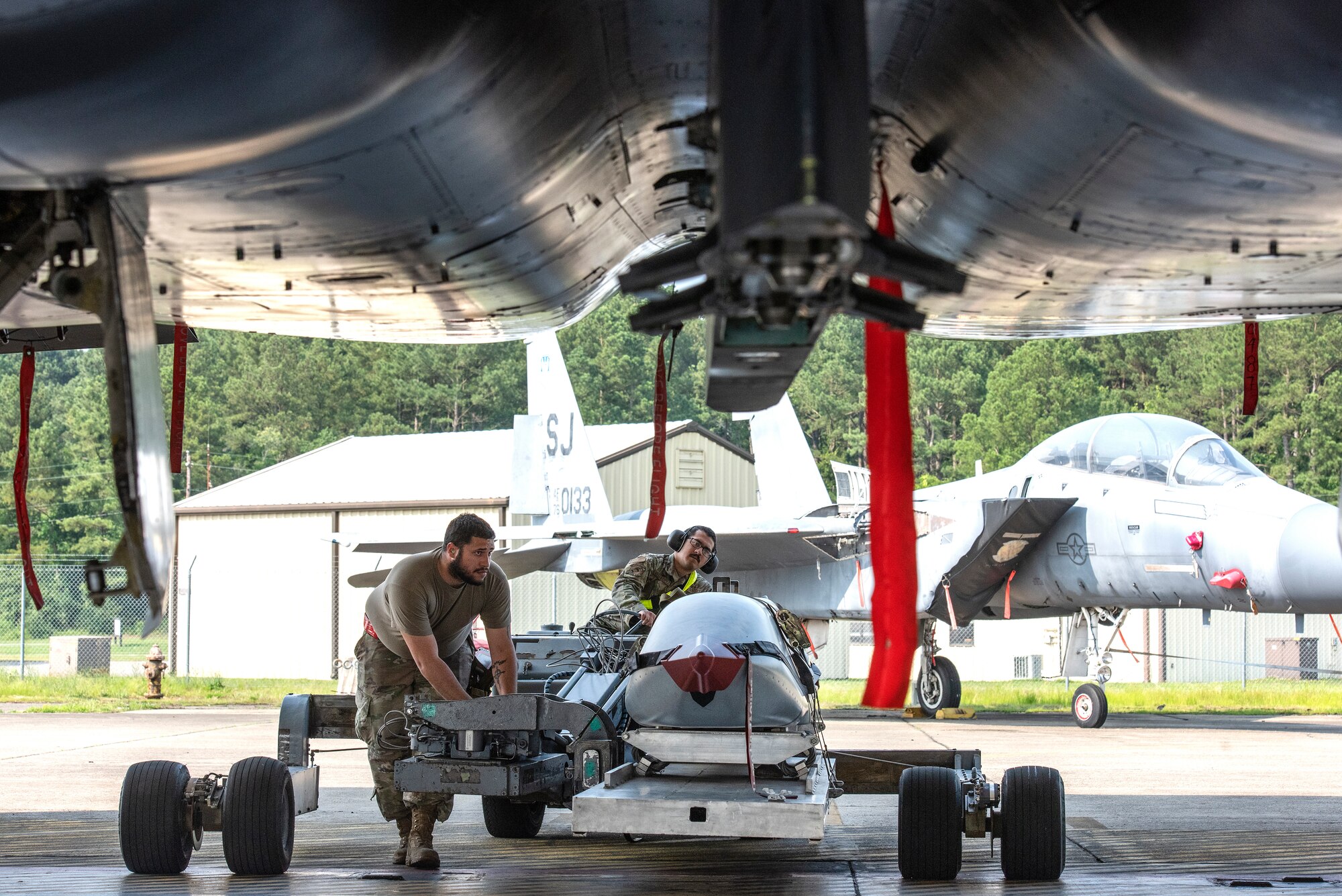Staff Sgt. Miguel Jiminez Flores, left, 336th Fighter Generation Squadron weapons load crew chief, guides Airman 1st Class Jean Vega-Lopez, 336th FGS weapons load crew member, as he transports an unarmed practice [AGM-158 JASSM] munition toward an F-15E Strike Eagle.