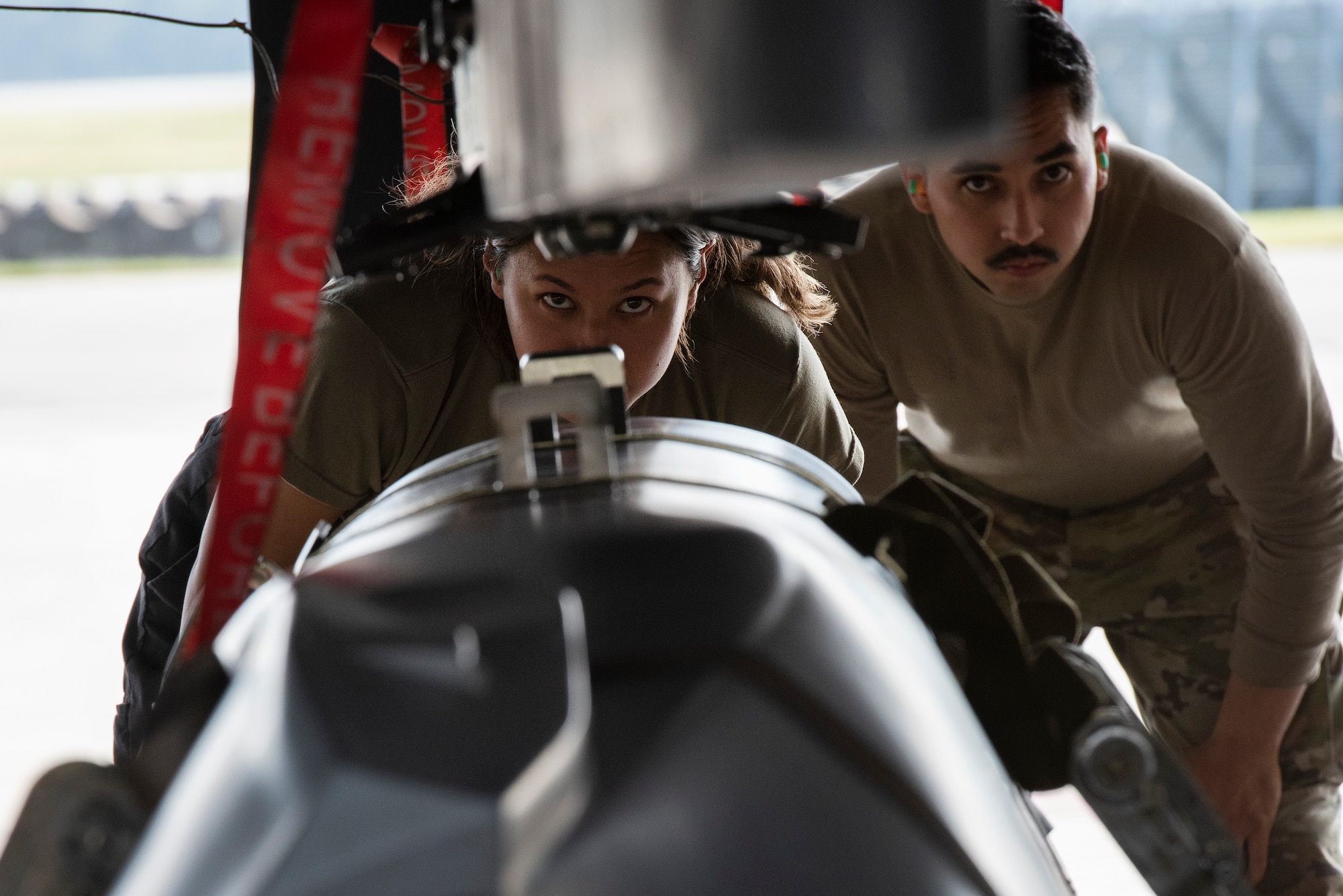 Senior Airman Cassandra Romero, center, 333rd Fighter Generation Squadron weapons load crew member, lines up an unarmed practice [AGM-158 JASSM] munition to load it onto an F-15E Strike Eagle as Staff Sgt. Alexandro Diaz, right, 4th Maintenance Group loading standardization crew member, evaluates her during a weapons standardization load evaluation.