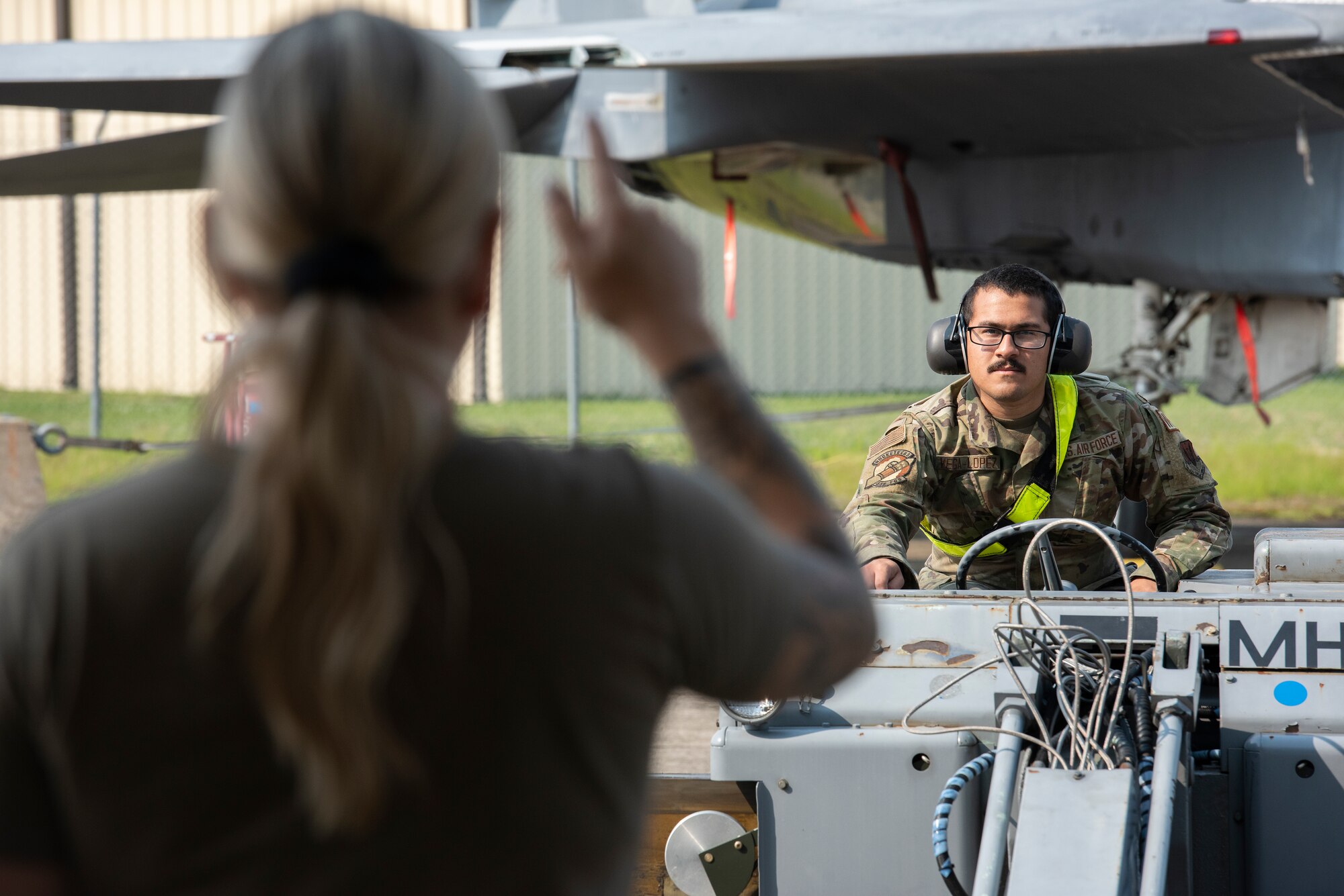 Airman 1st Class Jean Vega-Lopez, background, 336th Fighter Generation squadron weapons load crew member, operates a loading vehicle.