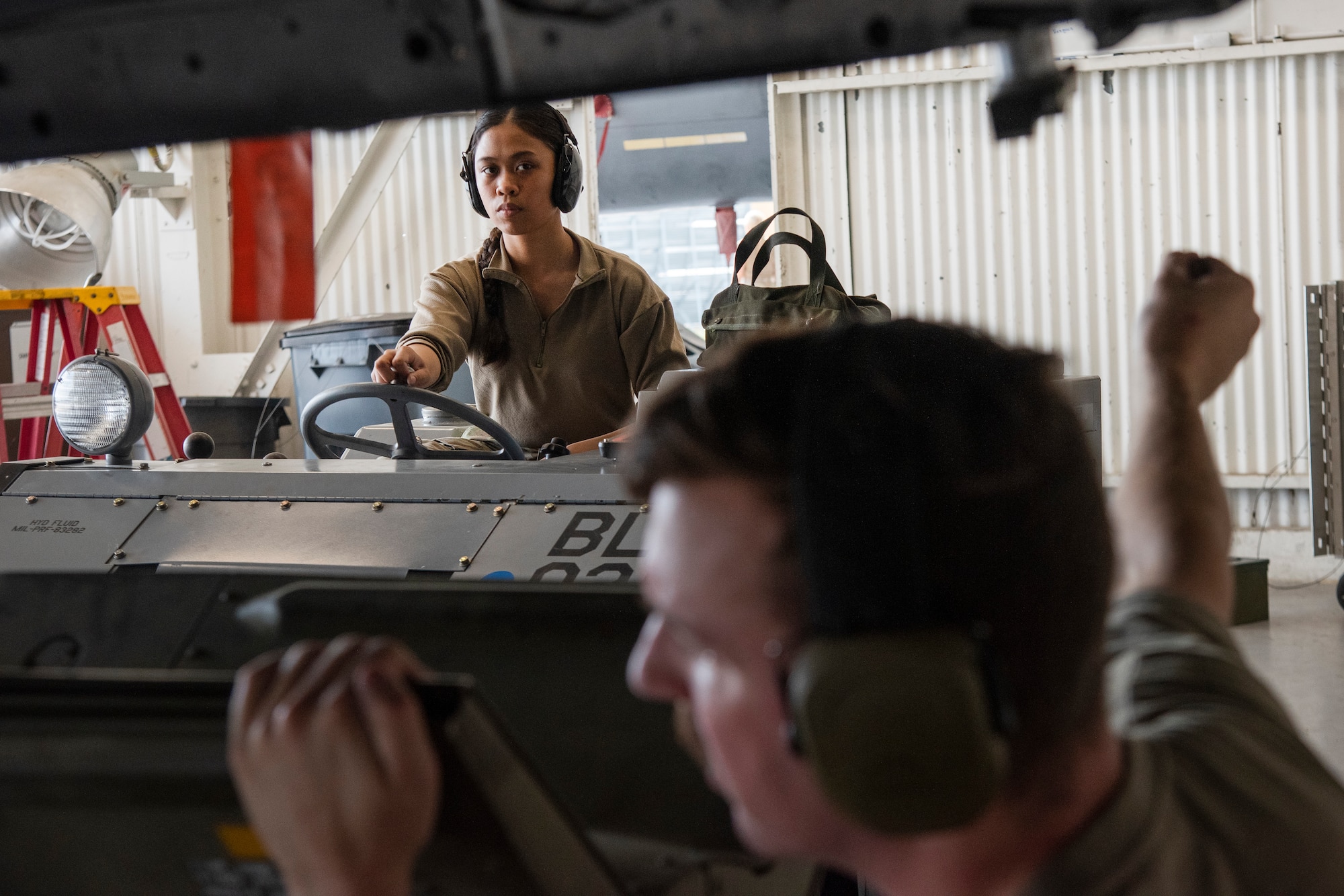Airman 1st Class Alexandria Magtibay, background, 336th Fighter Generation Squadron weapons load crew member, transports an unarmed practice munition to an F-15E Strike Eagle.