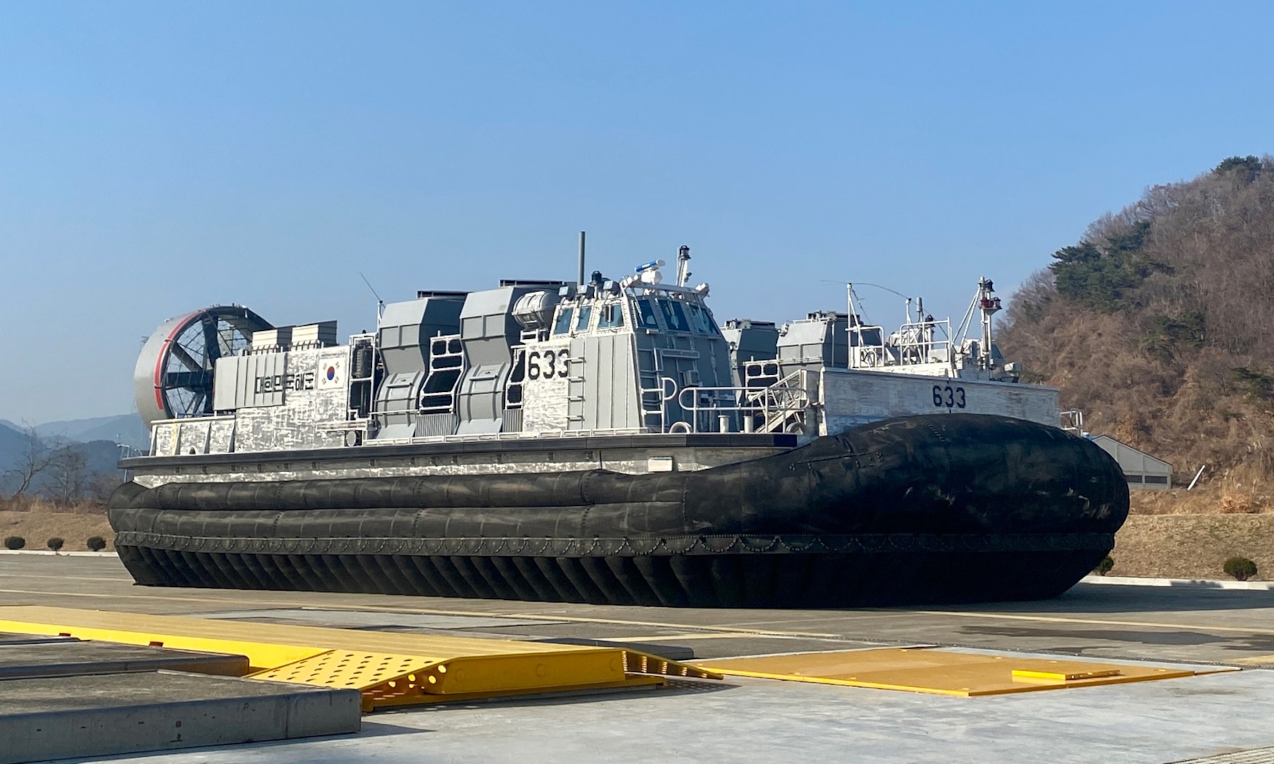 The Landing Ship Fast II (LSF-II) craft 633 is shown after inflating the skirting. This December 2022 operation tested the Command, Control, Communication, Computers, and Navigation (C4N) system for operating the engine and running the lift fans used to inflate the bags in the skirting, and the propellers and air ducts used to maneuver the craft on the tarmac. This is the first time the C4N operated as a system and actively controlled functions aboard the vessel. (courtesy photo provided by Hanjin Shipbuilding and Construction with permission from the Republic of Korea Defense Acquisition Program Administration)