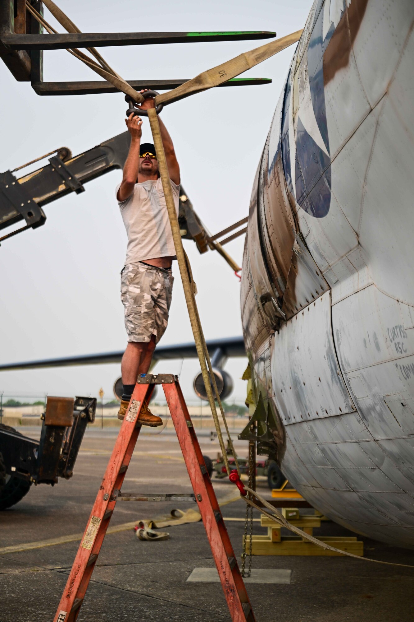 Jesse Bendt, a Worldwide Aircraft recovery lead, secures a strap around the body of a C-46 Commando at the Air Mobility Command Museum on Dover Air Force Base, Delaware, June 5, 2023. The C-46 was utilized for transporting personnel and cargo such as ammunition, fuel, light artillery and aircraft parts in the China-Burma-India theater during World War II. (U.S. Air Force photo by Staff Sgt. Faith Barron)