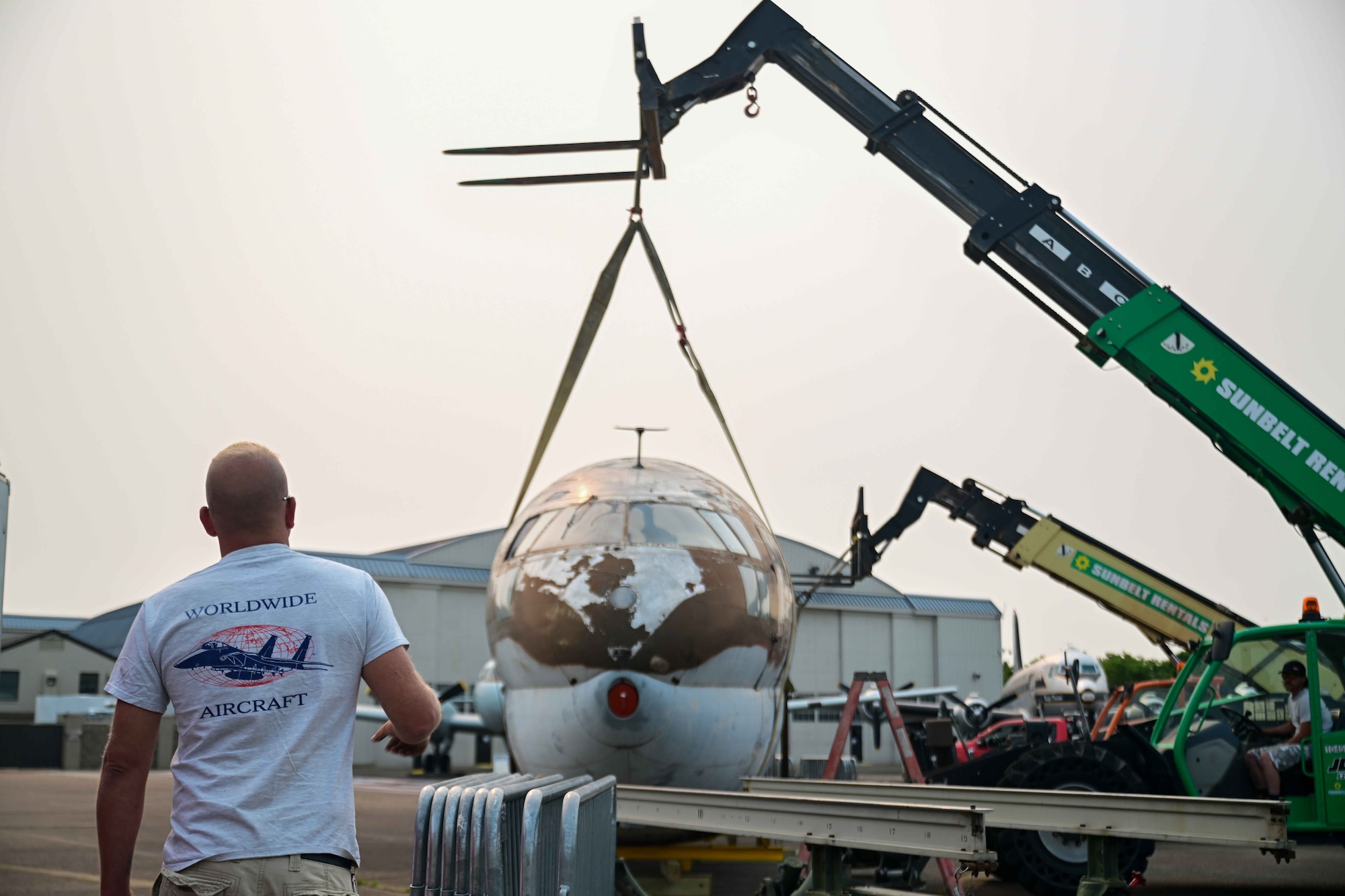 Jay Penry, a Worldwide Aircraft recovery lead, directs two forklift operators moving a C-46 Commando at the Air Mobility Command Museum on Dover Air Force Base, Delaware, June 5, 2023. The C-46 is currently undergoing the restoration process at the AMC Museum, which is expected to take up to two years. (U.S. Air Force photo by Staff Sgt. Faith Barron)