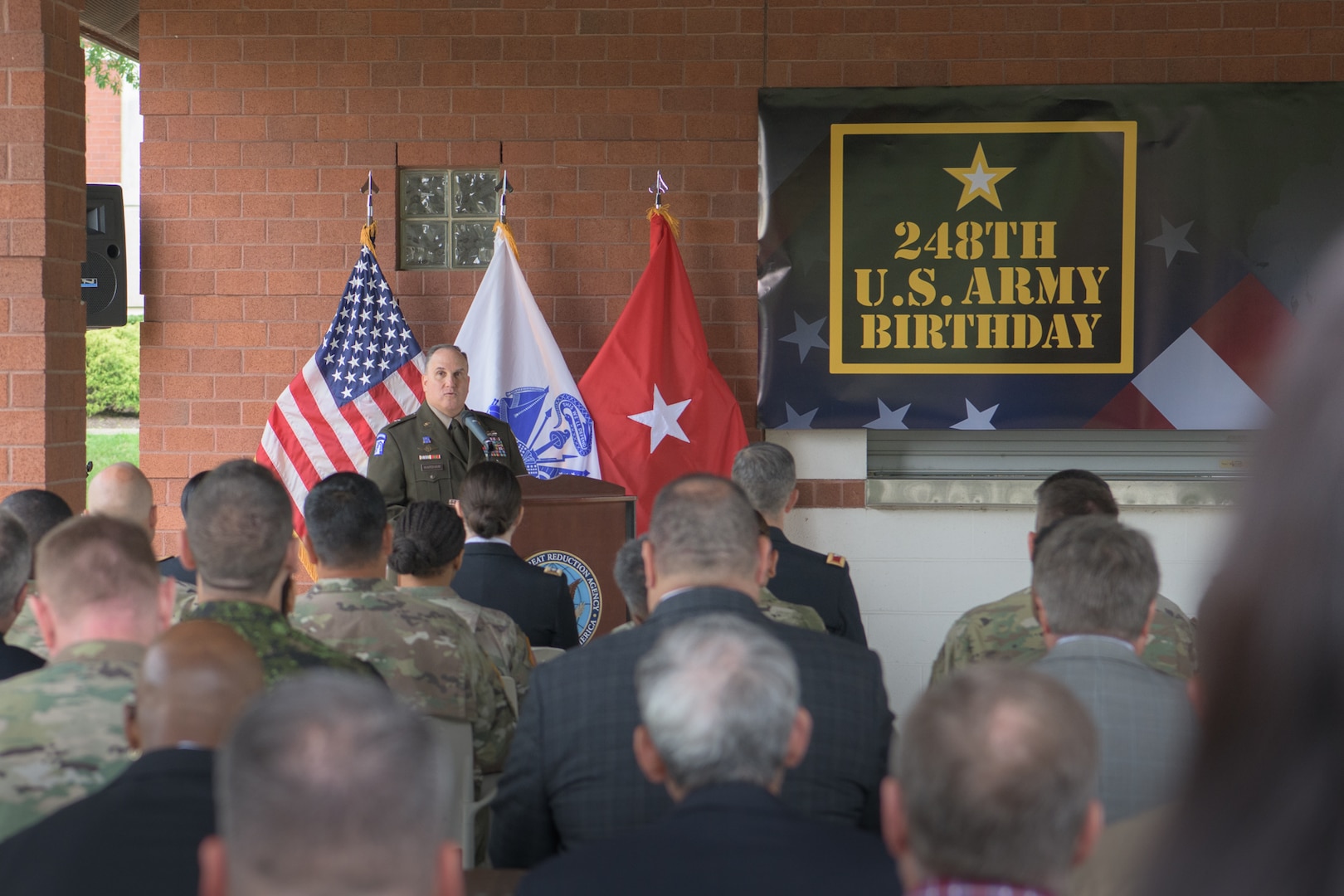An Army brigadier general addresses a crowd on a stage for an Army birthday ceremony.