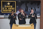 Three soldiers eat a piece of cake for the Army's birthday.