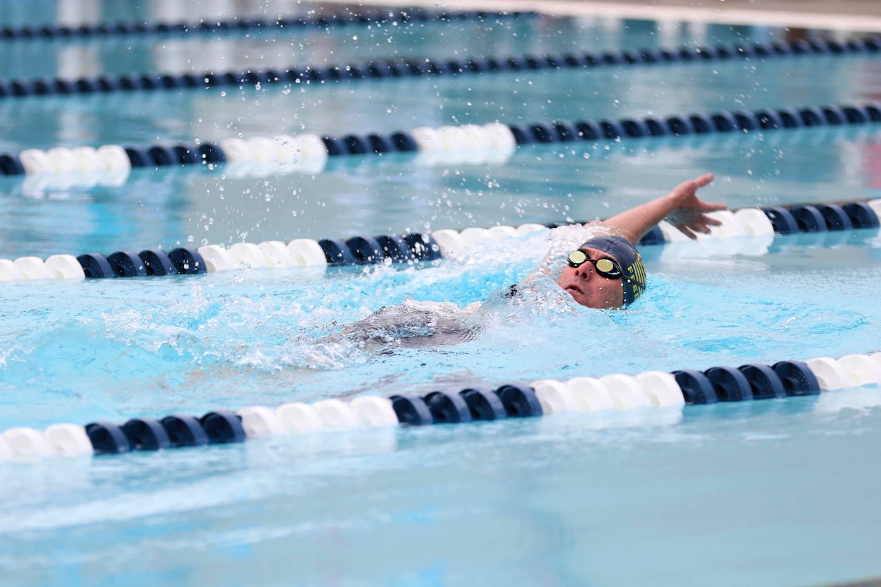 A Coast Guardsman backstrokes in a pool.