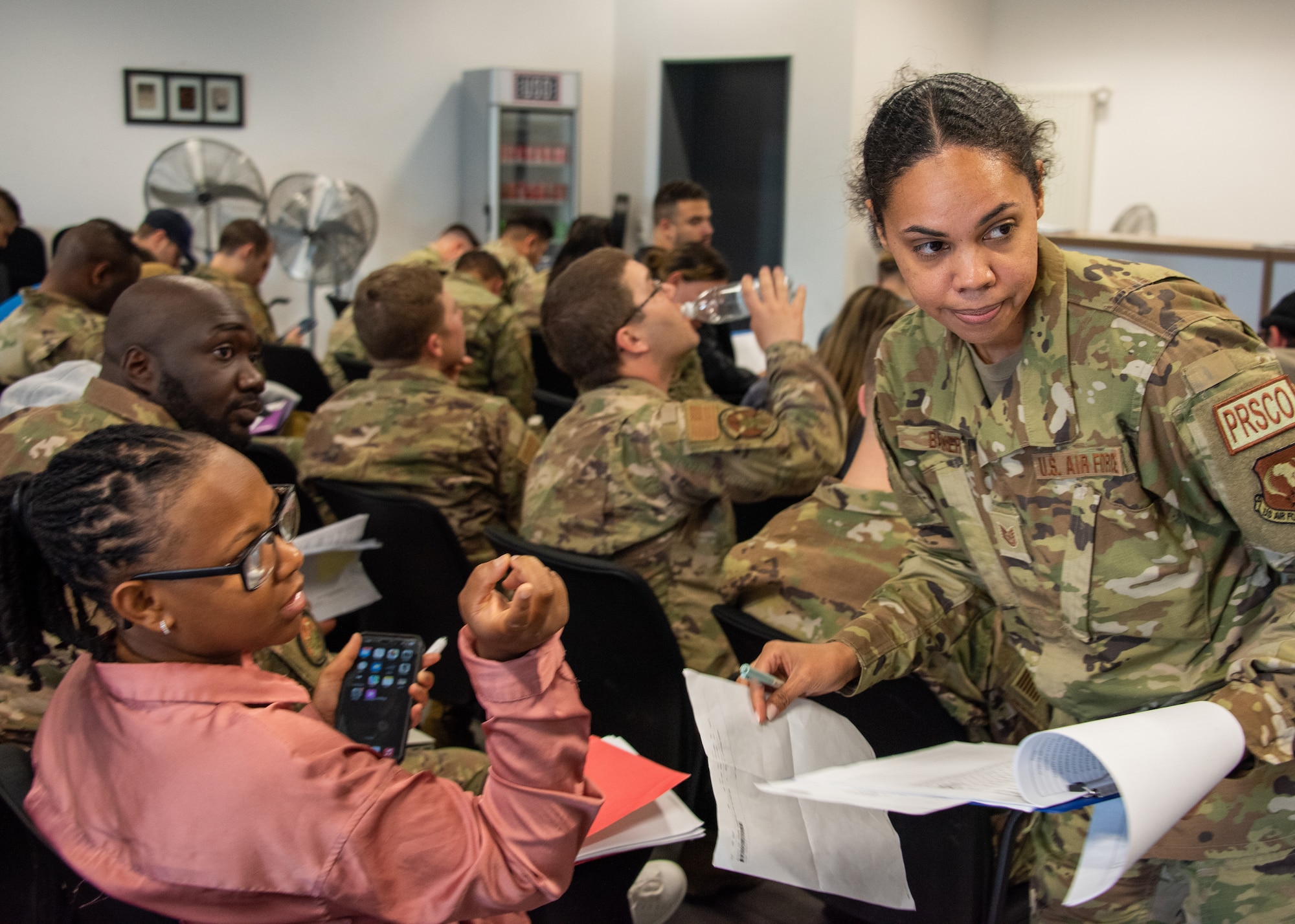 Tech Sgt. Ruby Baker, 406th Air Expeditionary Wing Personnel Support for Contingency Operations NCO, collects personnel documents from a 406th AEW deployer during an in-processing briefing at Ramstein Air Base, Germany, May 18, 2023.