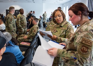 Master Sgt. Ieshea Lattimore, 406th Air Expeditionary Wing Staff Agency & A1 superintendent, left, and Master Sgt. Stephanie Williams Personnel Support for Contingency Operations team chief, collect and review in-processing documents from deployers at Ramstein Air Base, Germany, May 18, 2023.