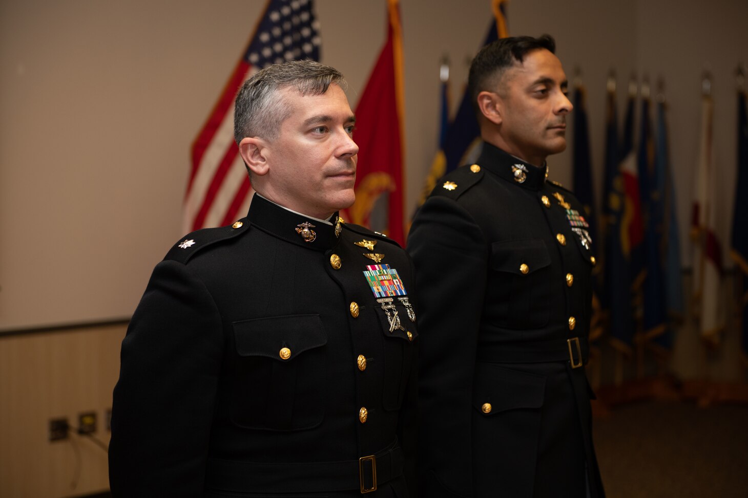 Lt. Col. James Corrington and Maj. Syed Rashid stand as the flyer's creed is read during their winging ceremony, March 23. Corrington and Rashid, both prior weapons systems officers (WSOs) earned their pilot wings as part of the Professional Flight Instructor Program and are entitled to wear the warfare devices of the Naval Aviator and the Naval Flight Officer.