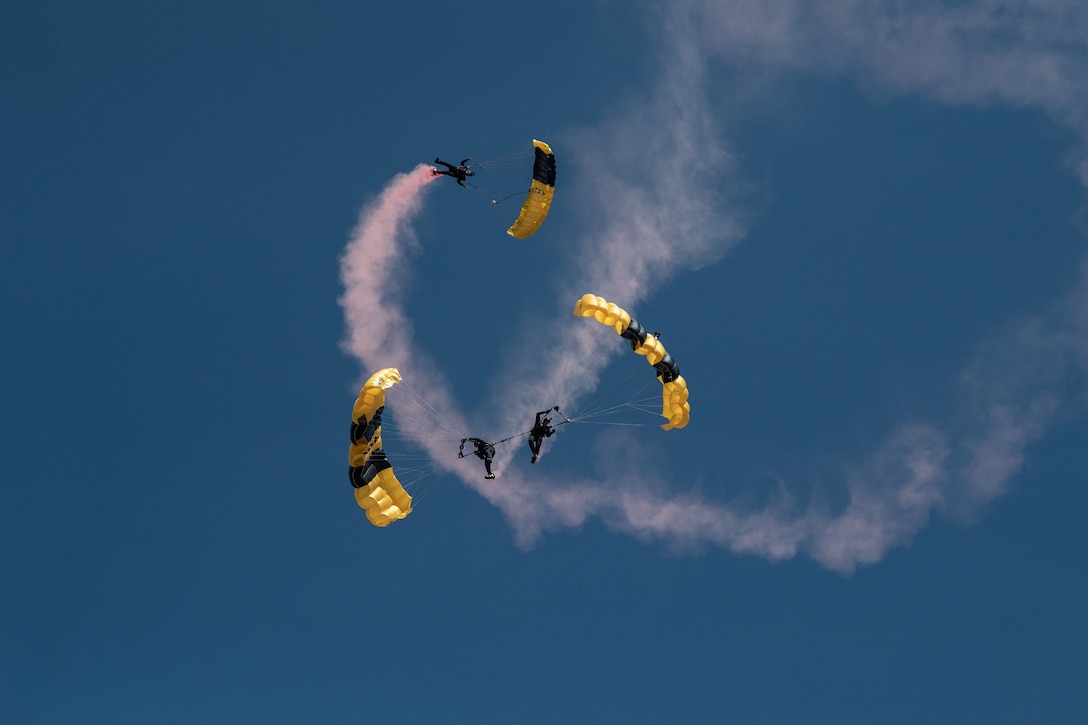 Three parachutists perform in the air.