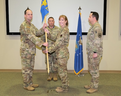 four uniformed military members stand on stand during change of command ceremony