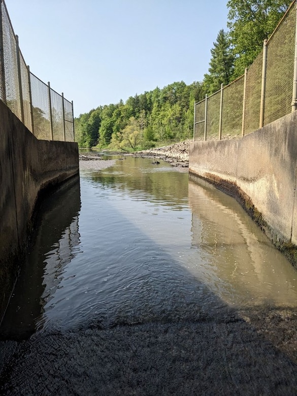 An inside perspective from the downstream conduit at the stilling basin and training walls in Saegertown, Pennsylvania, May 2023. Union City Dam was built in 1971 and is the only “dry” dam among the sixteen flood-control reservoirs operated by the Pittsburgh District, meaning it does not maintain a permanent pool. The dam is self-regulated and does not require staff to operate machinery from a control tower – the dam releases water via a conduit invert and if the pool level eclipses a set elevation, water is automatically released through the dam’s spillway crest. (U.S. Army Corps of Engineers photo by Ryan Hill)