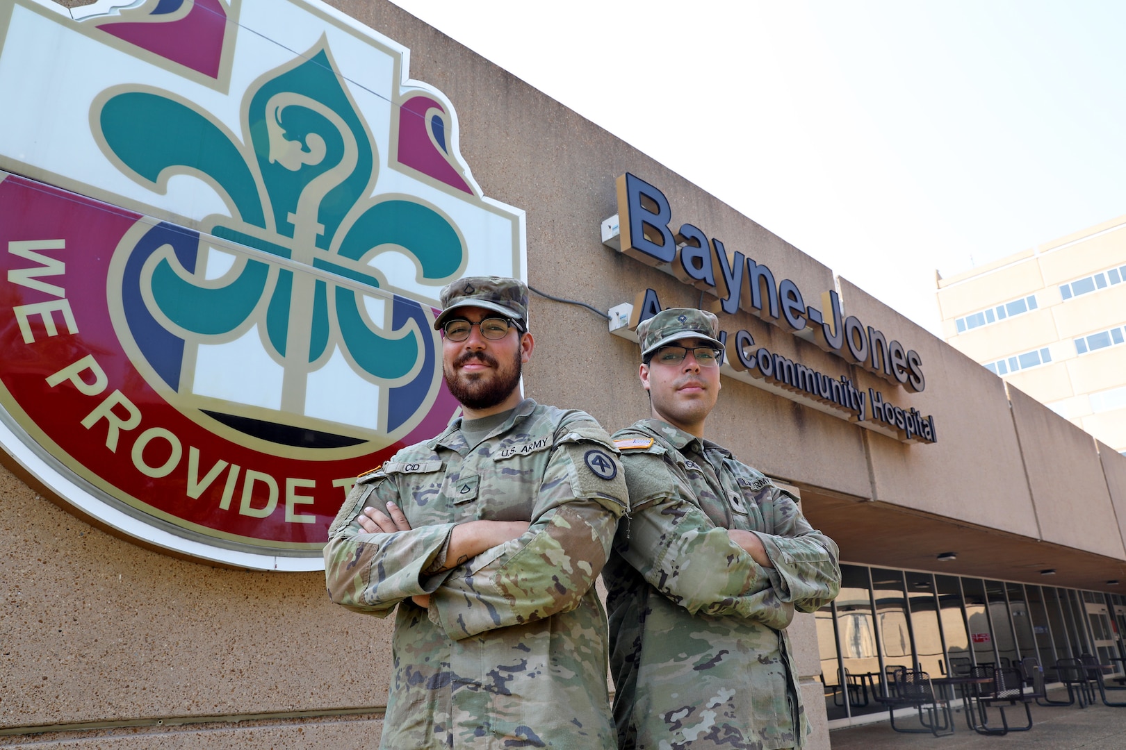 Twin brothers and Soldiers pose in front of the BJACH sign.