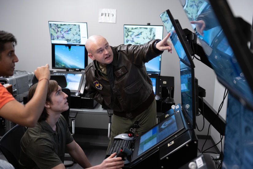 A man in uniform points to a computer screen.