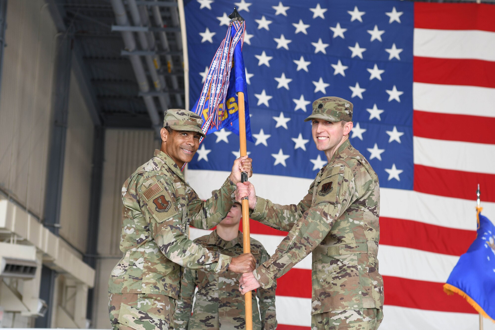 Two men in green uniforms hold onto a guidon.