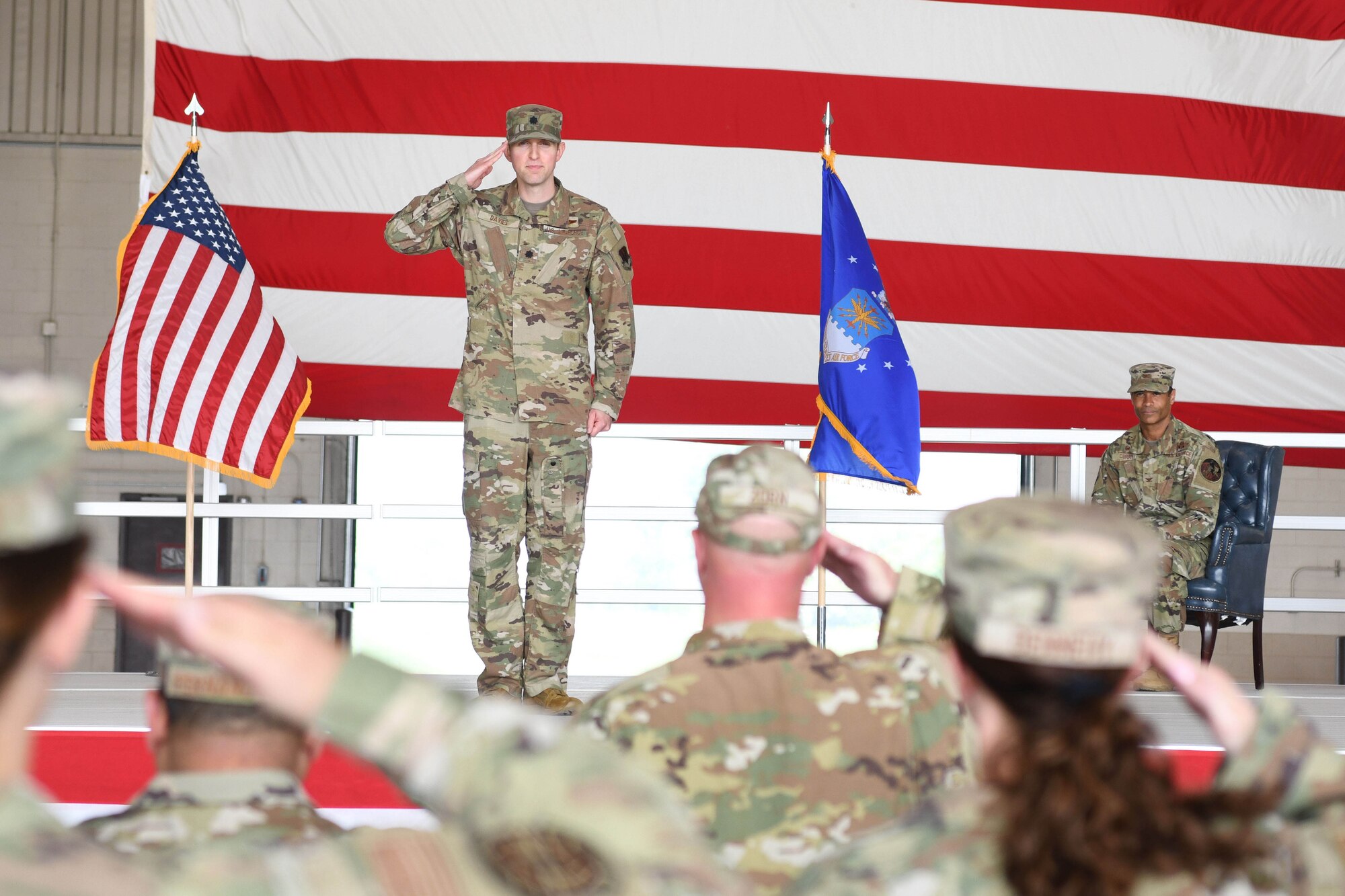 Man in green uniform salutes crowd.