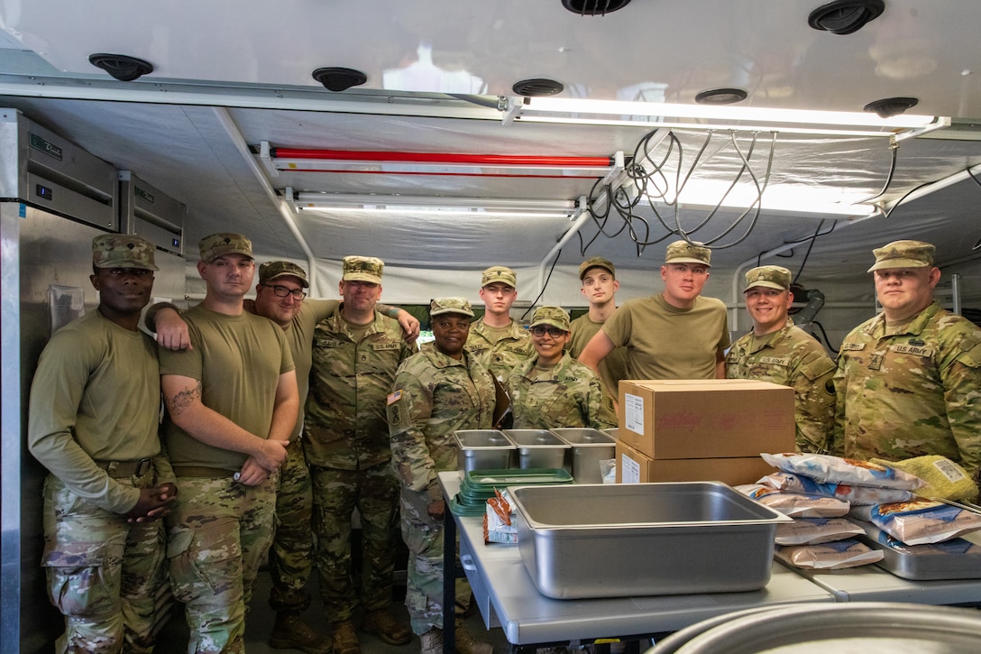 Soldiers of India Company, 429th Brigade Support Battalion, 75th Troop Command, pose for a photo in their containerized kitchen during the Regional Philip A. Connelly Field Feeding Competition at the Harlold L. Disney Training Center in Artemus, Kentucky on June 14, 2023. The Soldiers are competing against nine other states and territories National Guard field feeding units in the southeast United States for a chance to compete nationally against the other regions of the National Guard. (U.S. Army National Guard photo by Andy Dickson)