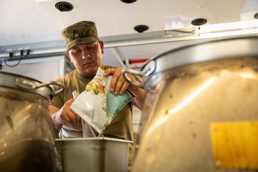 U.S. Army Sgt. Joshua Shofner of India Company, 429th Brigade Support Battalion, 75th Troop Command, adds ingredients to a pot in a containerized kitchen during the Regional Philip A. Connelly Field Feeding Competition at the Harlold L. Disney Training Center in Artemus, Kentucky on June 14, 2023. Shofner and the rest of India Company are competing against nine other states and territories National Guard field feeding units in the southeast United States for a chance to compete nationally against the other regions of the National Guard. (U.S. Army National Guard photo by Andy Dickson)