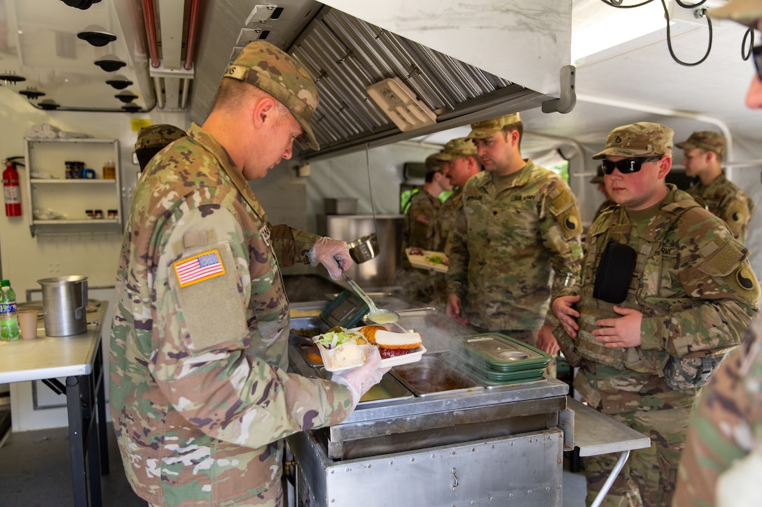 Soldiers of India Company, 429th Brigade Support Battalion, 75th Troop Command, pose for a photo in their containerized kitchen during the Regional Philip A. Connelly Field Feeding Competition at the Harlold L. Disney Training Center in Artemus, Kentucky on June 14, 2023. The Soldiers are competing against nine other states and territories National Guard field feeding units in the southeast United States for a chance to compete nationally against the other regions of the National Guard. (U.S. Army National Guard photo by Andy Dickson)