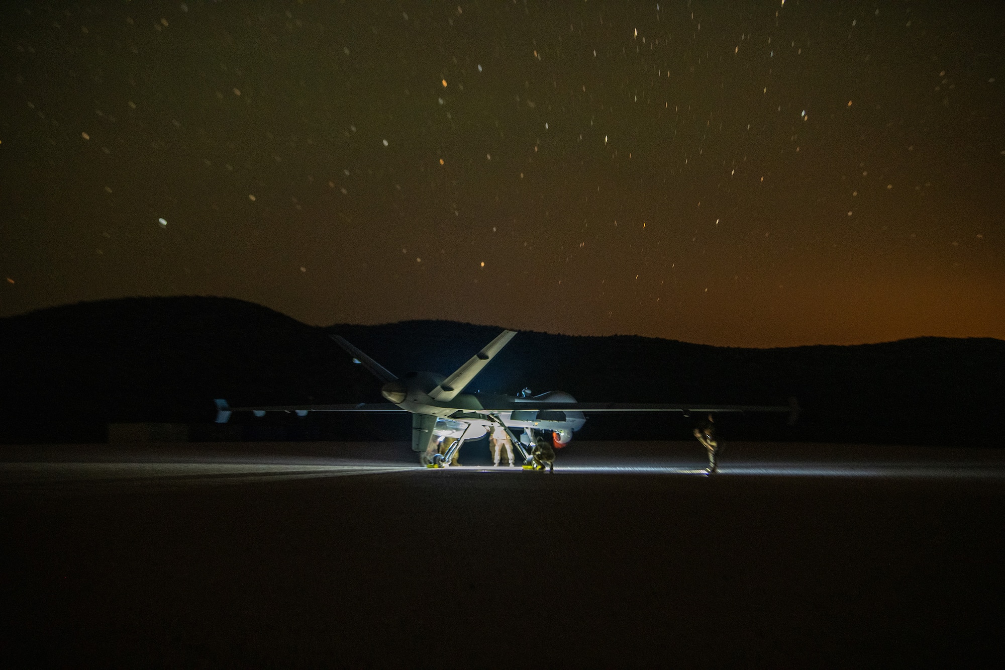 aircraft sits on dirt path at night under the stars