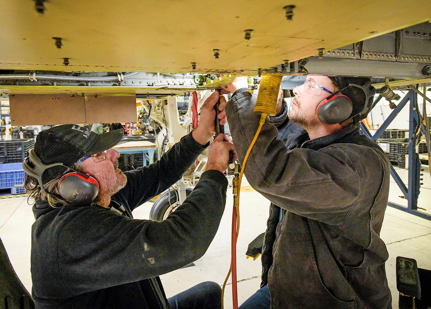 Sheet metal mechanics Keenen Wright and Heath Bryant, assigned to Fleet Readiness Center Southeast’s F-5 Production Line, fit, drill and install the landing gear door hinge assembly on an F-5N Tiger II.