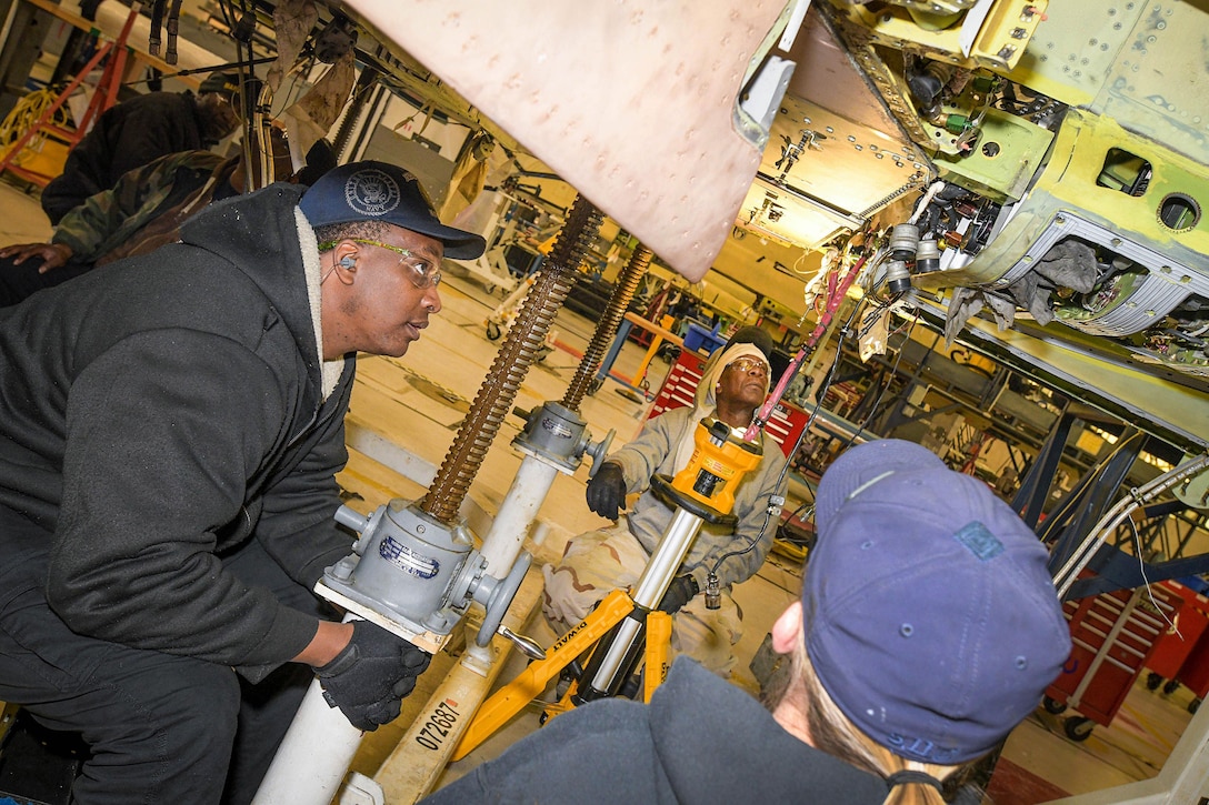 Artisans assigned to Fleet Readiness Center Southeast’s F-5 Production Line prepare to remove the wing of an F-5N Tiger II aircraft for inspection.