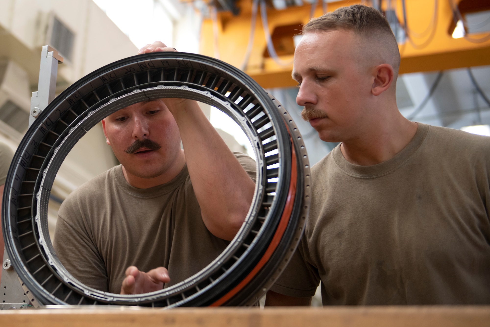 Staff Sgt. Brandon Mayer, left, and Senior Airman Matthew Wgeishofski, 18th Component Maintenance Squadron central repair facility technicians, examine the high pressure turbine shroud from a 25th Fighter Squadron A-10Thunderbolt II engine at Kadena Air Base, Japan, Aug. 30, 2022. The 18th CMS houses the only A-10 engine backshop in the Pacific Air Forces area of responsibility. Each year the Airmen service over a dozen of these engines from Osan Air Base. (U.S. Air Force photo by Senior Airman Jessi Roth)