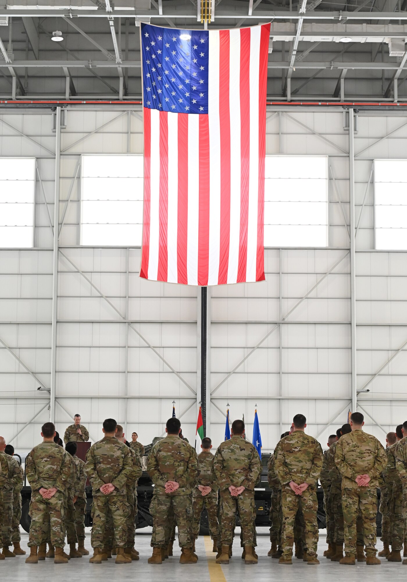 A photo of people standing in formation with a flag in the background.