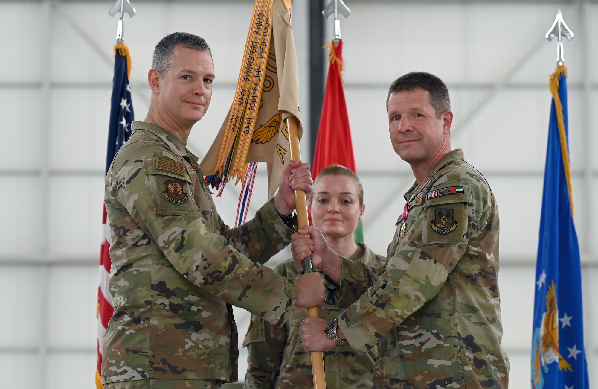 A photo of two people on stage holding the guidon.