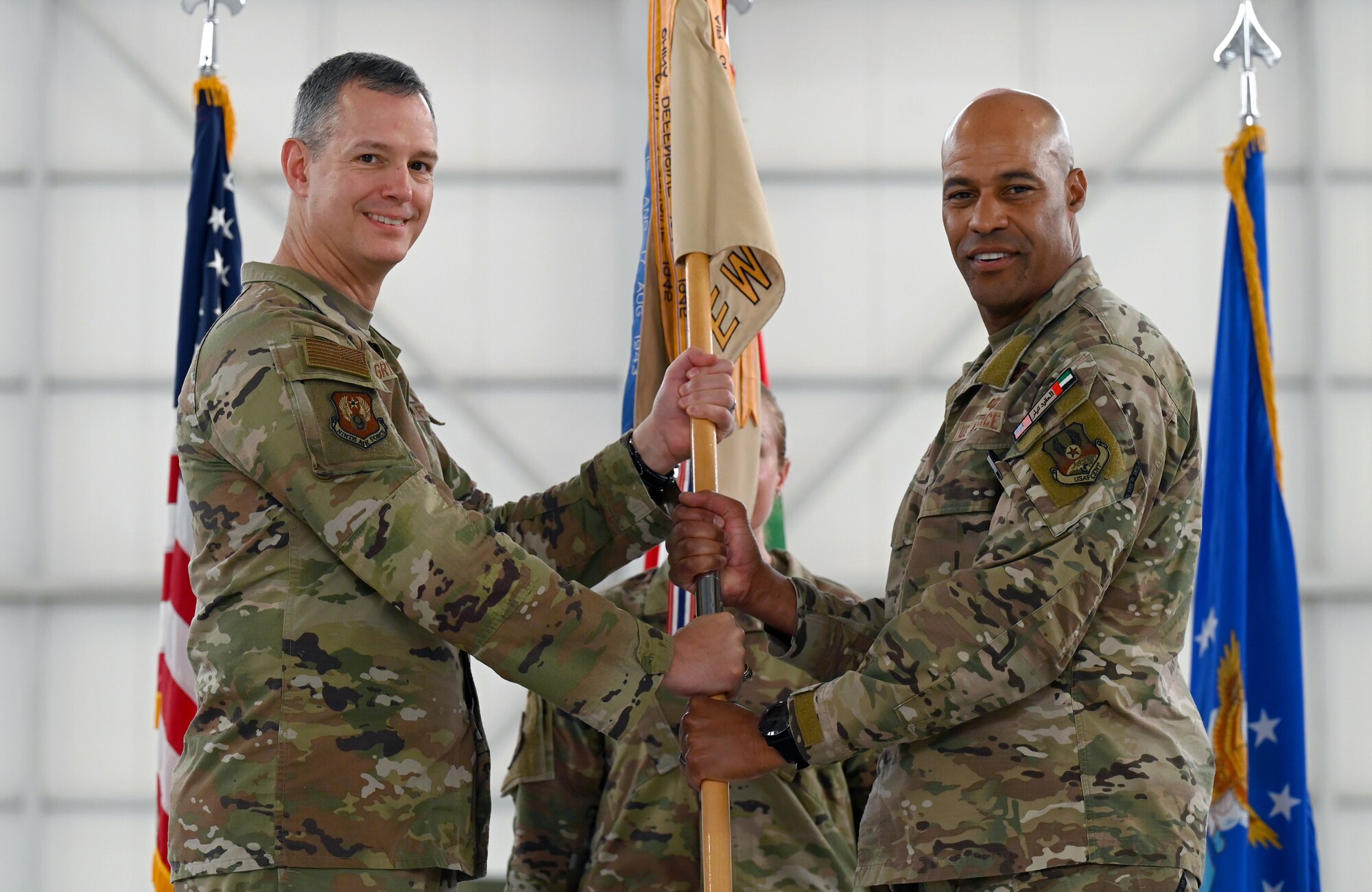 A photo of two people on stage holding the guidon.