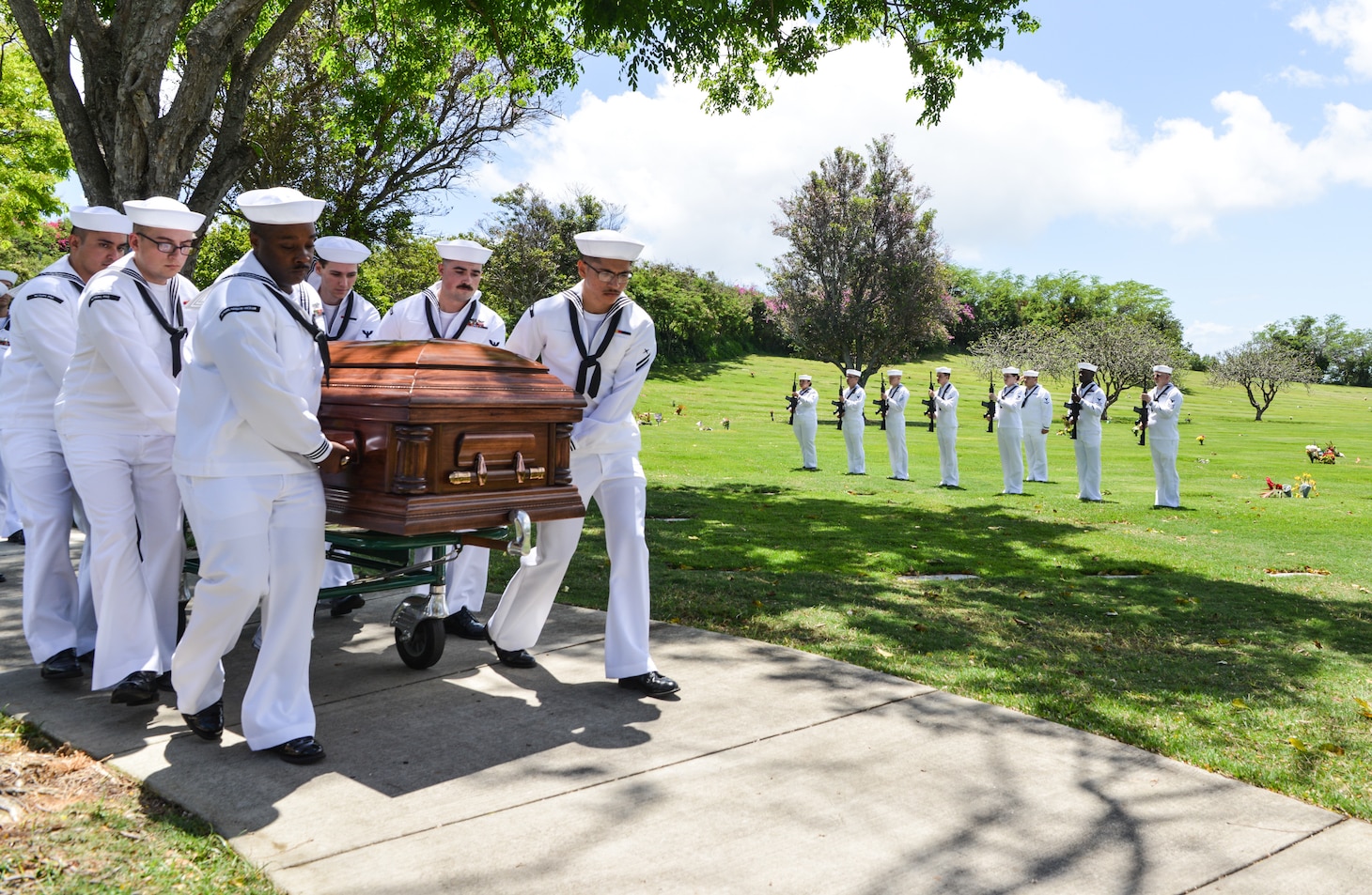 U.S. Navy Sailors assigned to Navy Region Hawaii and the Defense POW/MIA Accounting Agency (DPAA) move a casket toward a hearse during an interment at the National Memorial Cemetery of the Pacific, Honolulu, Hawaii, April 13, 2023. The cemetery allows all members of the armed forces who have met a minimum active duty service requirement to be buried there. (U.S. Air Force photo by Staff Sgt. David Owsianka)