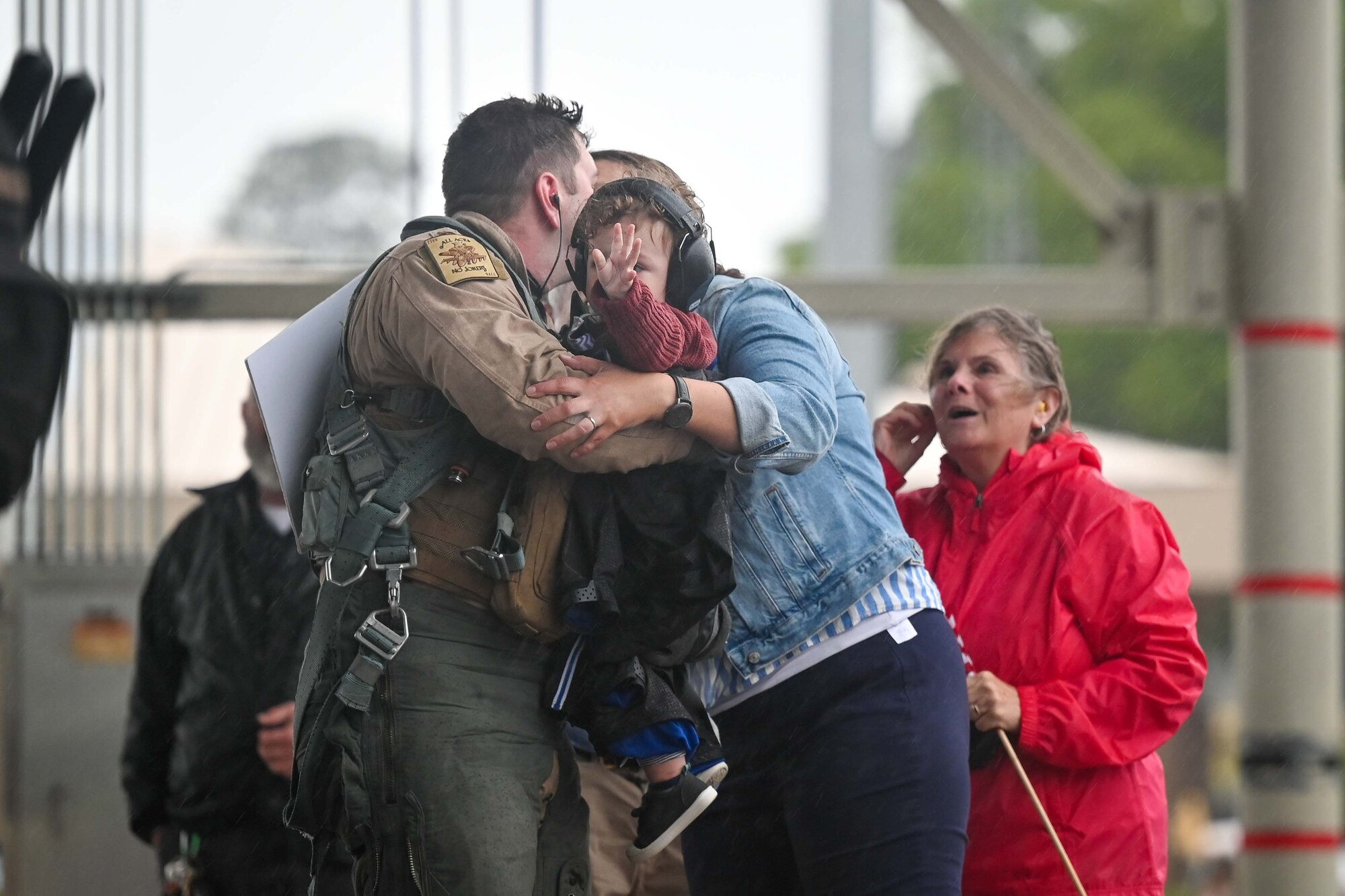 A pilot embraces his wife and child after redeploying to Shaw.