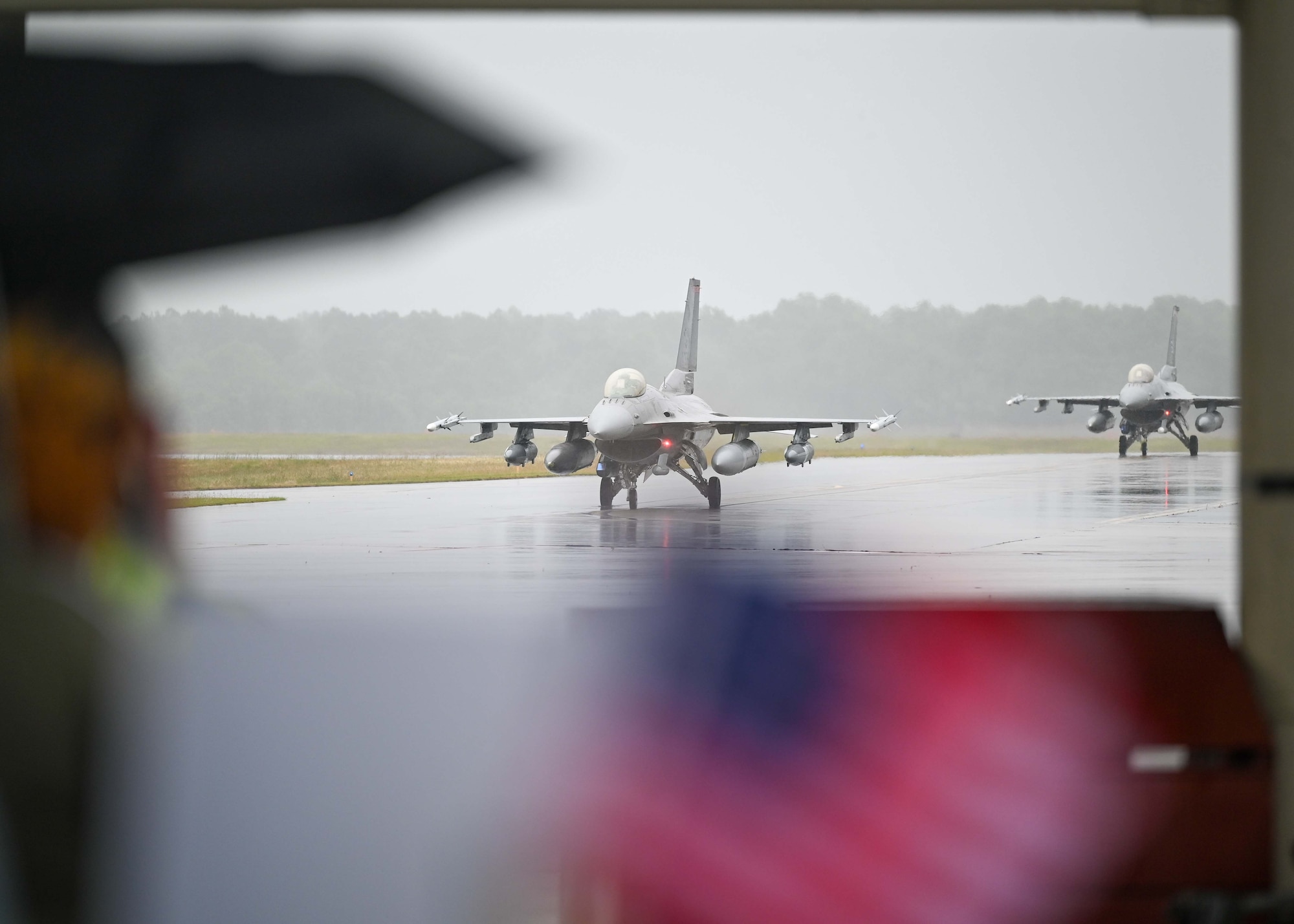 Redeploying jets taxi on the flightline while family members wait with commemorative signs.