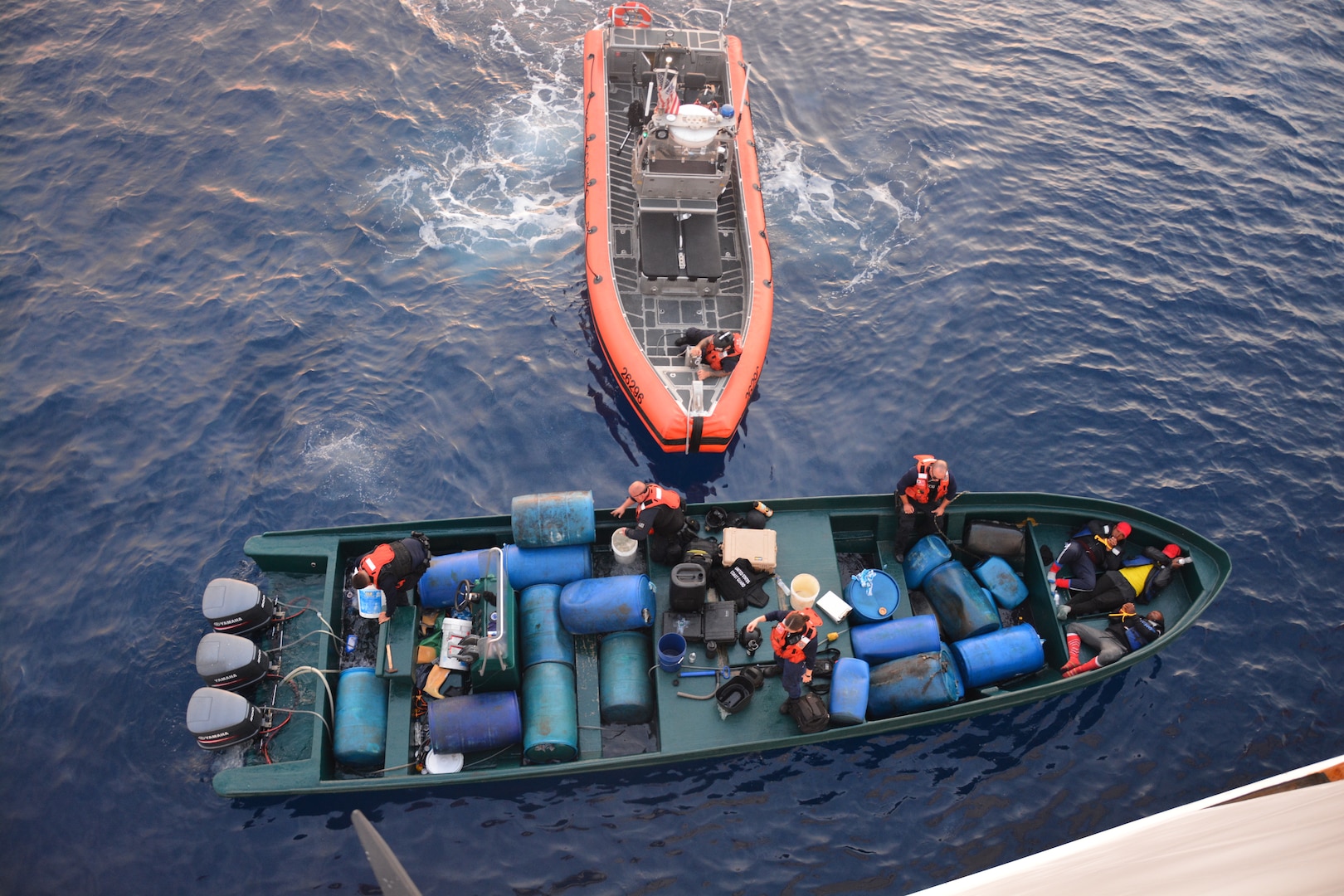 The Coast Guard Cutter Alert (WMEC 630) boarding Team uses buckets to scoop water out of go-fast vessel after the suspected drug smugglers attempted to scuttle the vessel in the Eastern Pacific Ocean May 26, 2023. The Coast Guard Cutter Alert crews actions and damage control skills prevented loss of evidence. (U.S. Coast Guard photo by Ens. Samuel Severson)