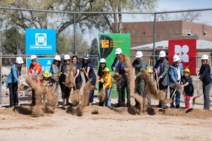 People wearing hardhats, holding shovels, and tossing dirt.