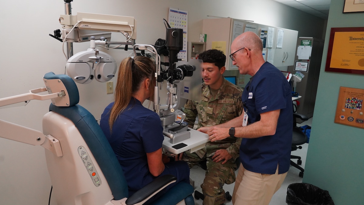 Dr. Steven Weekes, 88th Operational Medical Readiness Squadron optometrist, teaches Airman 1st Class Ethan Cortez, Optometry Flight technician, how to work a machine at Wright-Patterson Medical Center on June 13, 2023. The squadron “dominates the dirty work” by ensuring Airmen and military members are medically ready to execute their missions in home-base and deployed locations. (U.S. Air Force photo by Kenneth J. Stiles)