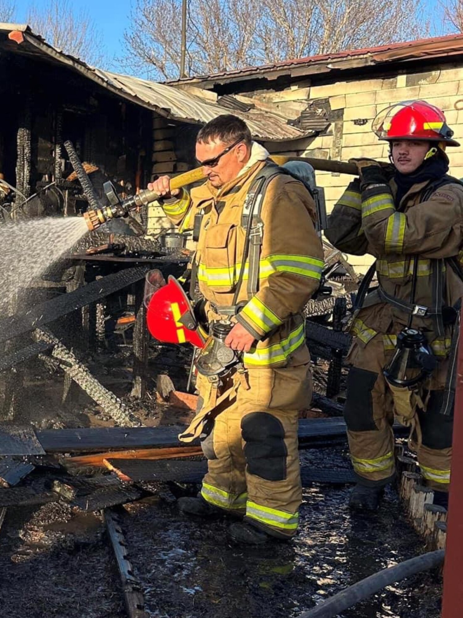 U.S. Air Force Staff Sgt. Branden Fry (right), Logistics Readiness Squadron ground transporter, puts out a fire with his father, Branden Fry (left), 97th Maintenance Squadron hydraulics systems mechanic, in Blair, Oklahoma, in April 2023. Bryson has served alongside his father as a volunteer firefighter since he was 18 years old. (Courtesy photo by Branden Fry)