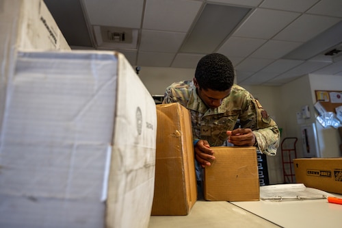 A photo of an Airman writing on a package.