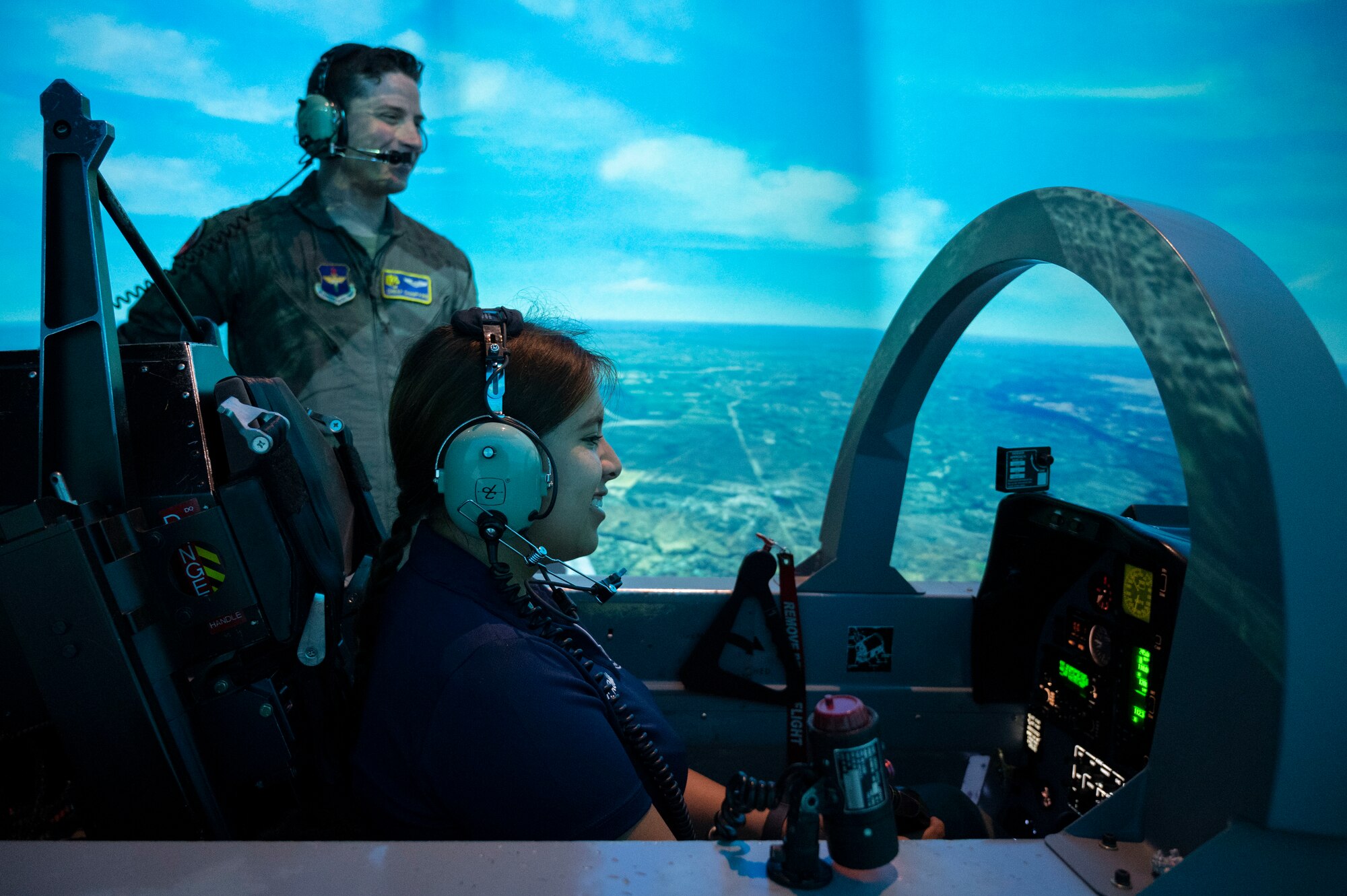 U.S. Air Force Capt. John Champagne (left), 85th Flying Training Squadron flight simulator instructor, teaches Carla Robles, Del Rio High School Junior Reserve Officer’s Training Corps cadet, how to fly a T-6A Texan II flight simulator at Laughlin Air Force Base, Texas, June 7, 2023. Robles visited Laughlin to gain insight into leading Laughlin’s mission and service members towards success under the guidance of Col. Kevin Davidson, 47th Flying Training Wing commander. (U.S. Air Force photo by Airman 1st Class Kailee Reynolds)