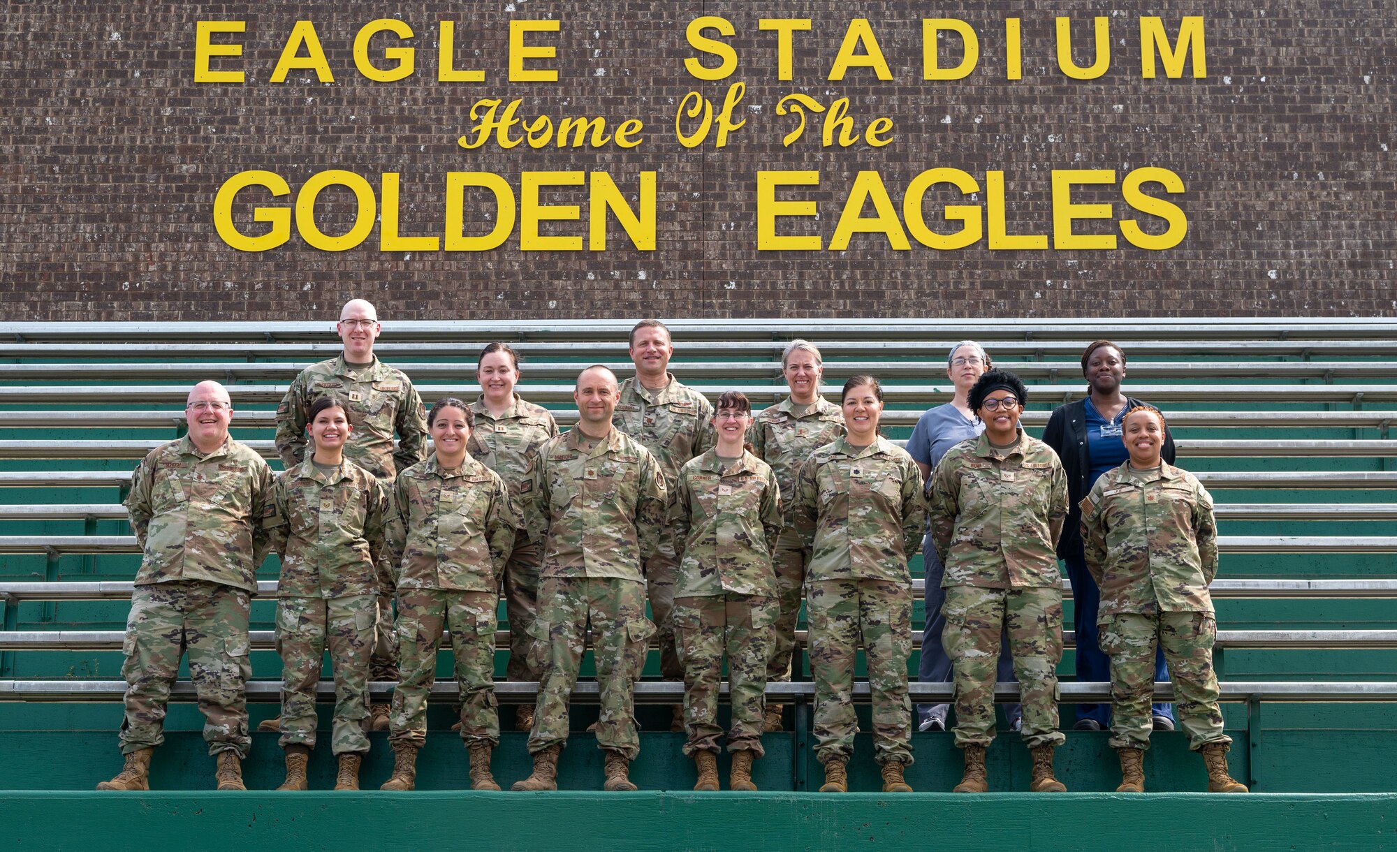 A group of 14 Airmen stand on bleachers