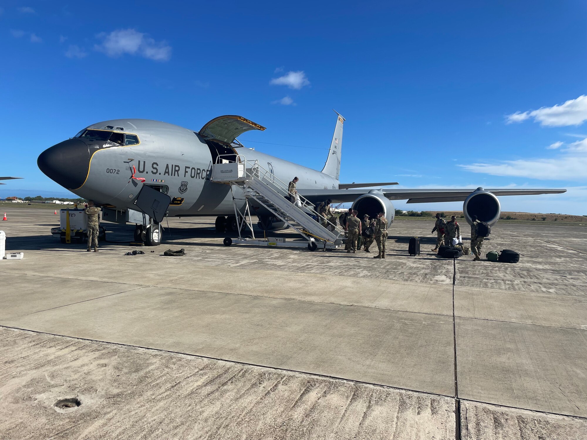 Troops unload a plane on a flight line.